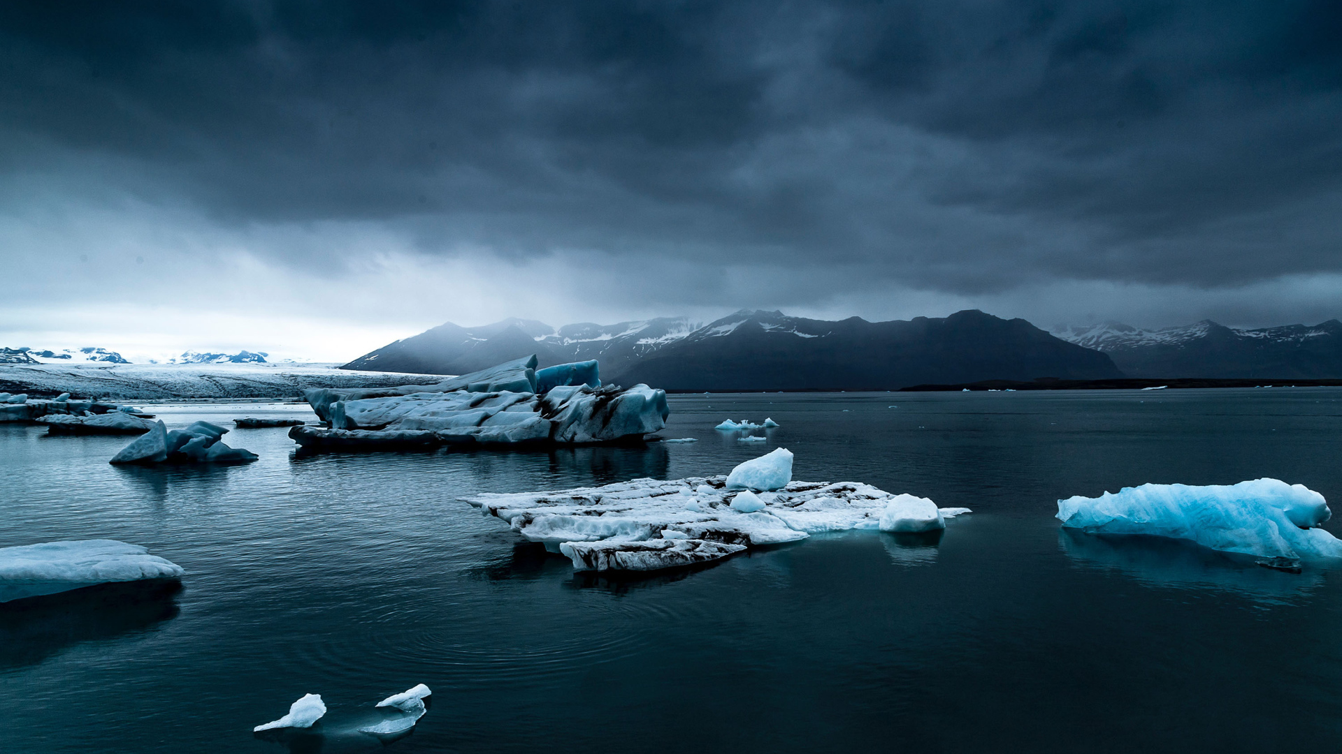 Large blue ice floes in the water under a cloudy sky