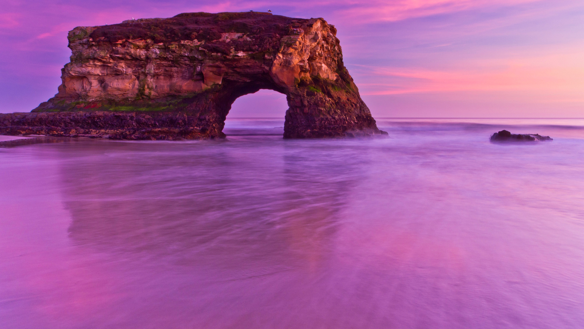 Гора с аркой в океане на фоне красивого неба