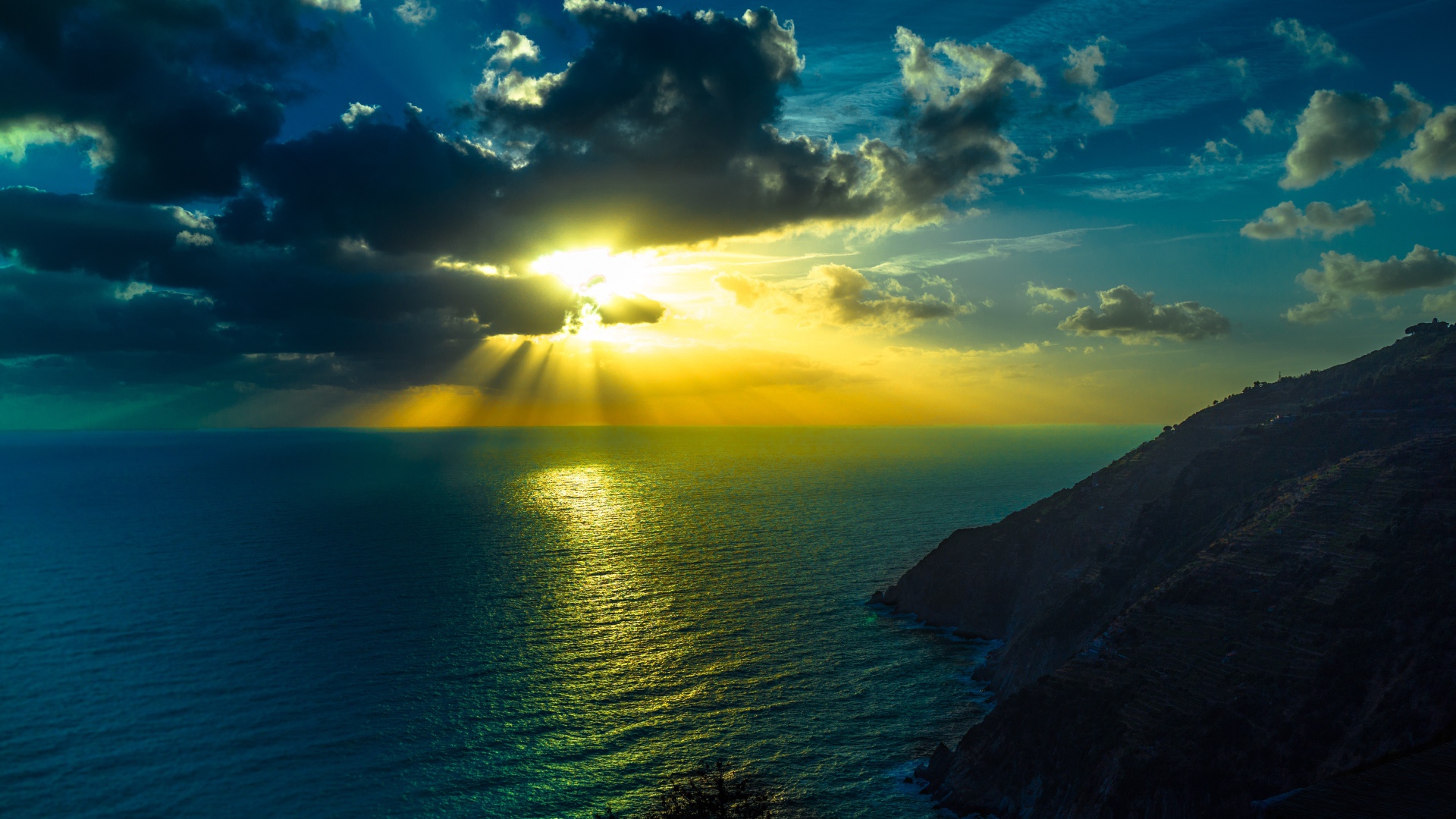 Лучи яркого солнца пробиваются сквозь облака над морем