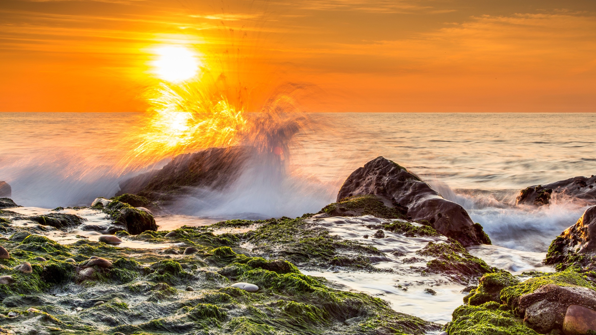 Бушующие волны в море бьются об камни на закате