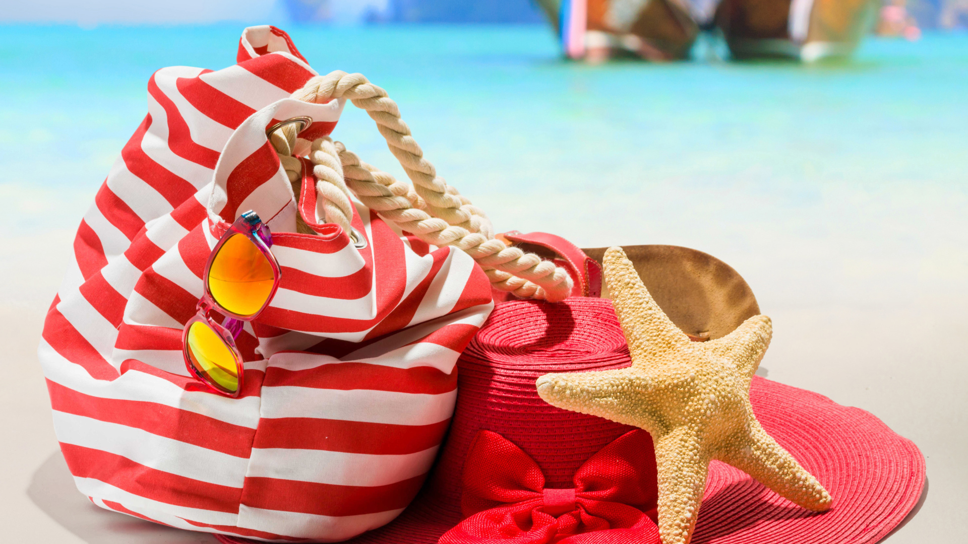 Большая красная шляпа с сумкой и морской звездой на пляже