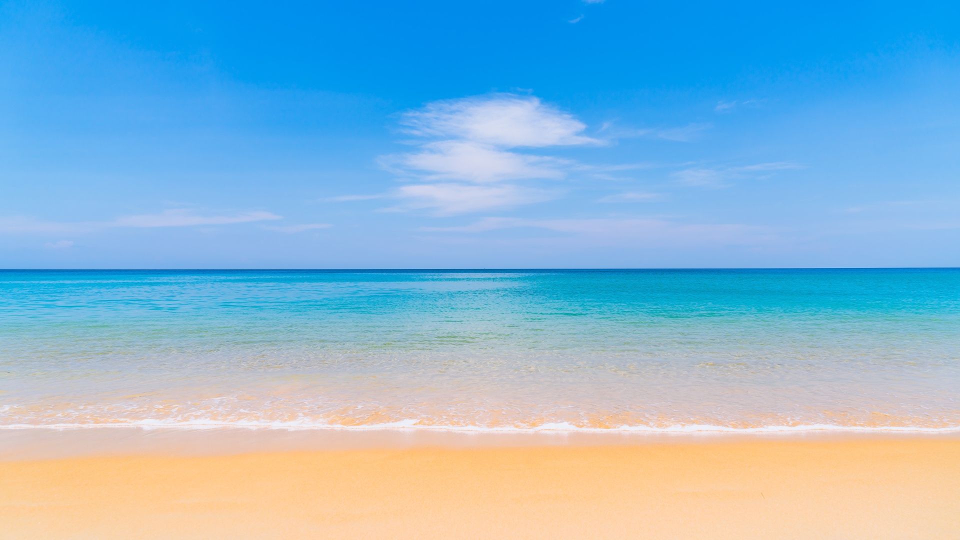 Желтый песок у лазурного океана под голубым небом