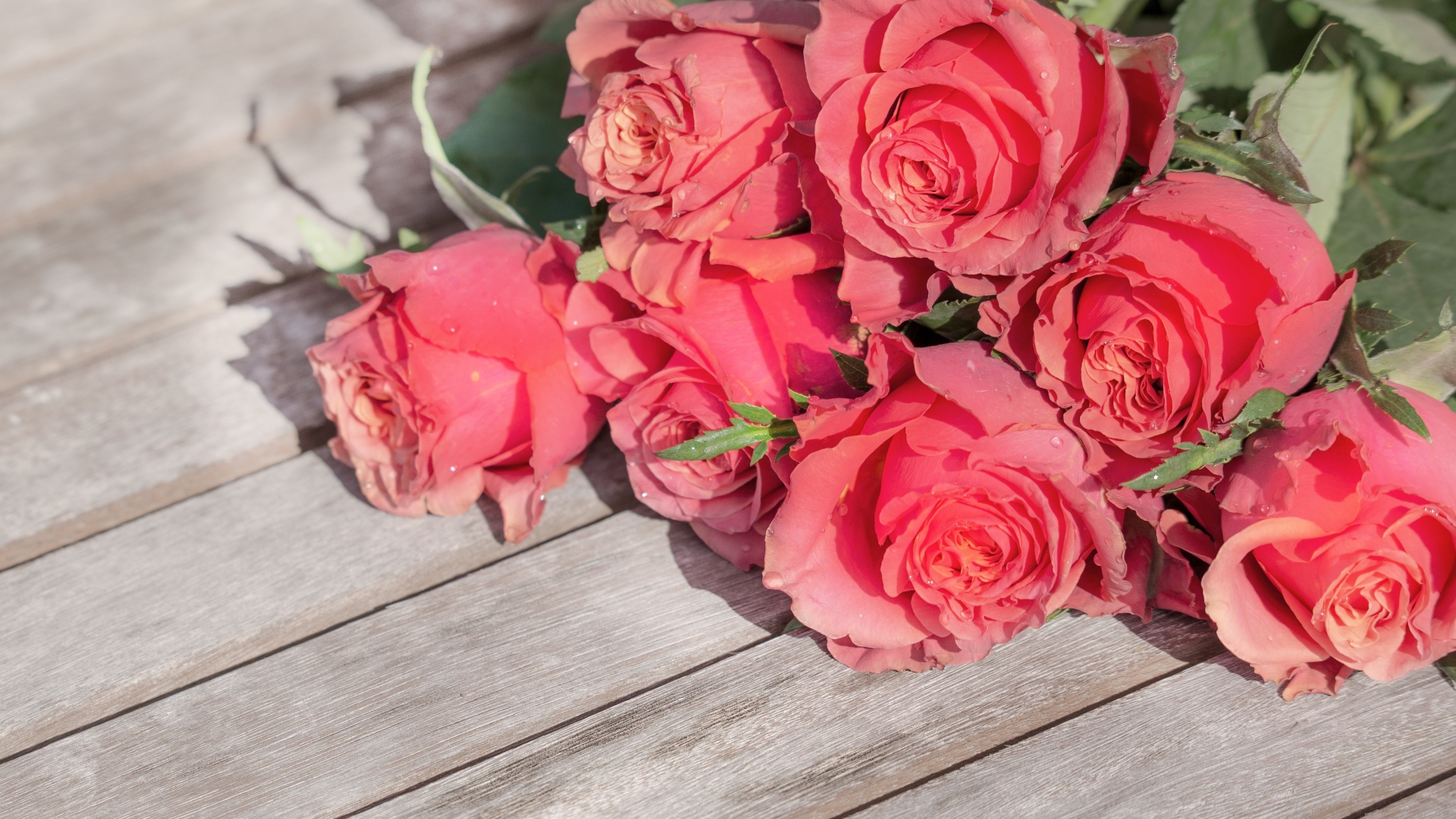 Букет розовых роз лежит на деревянной поверхности