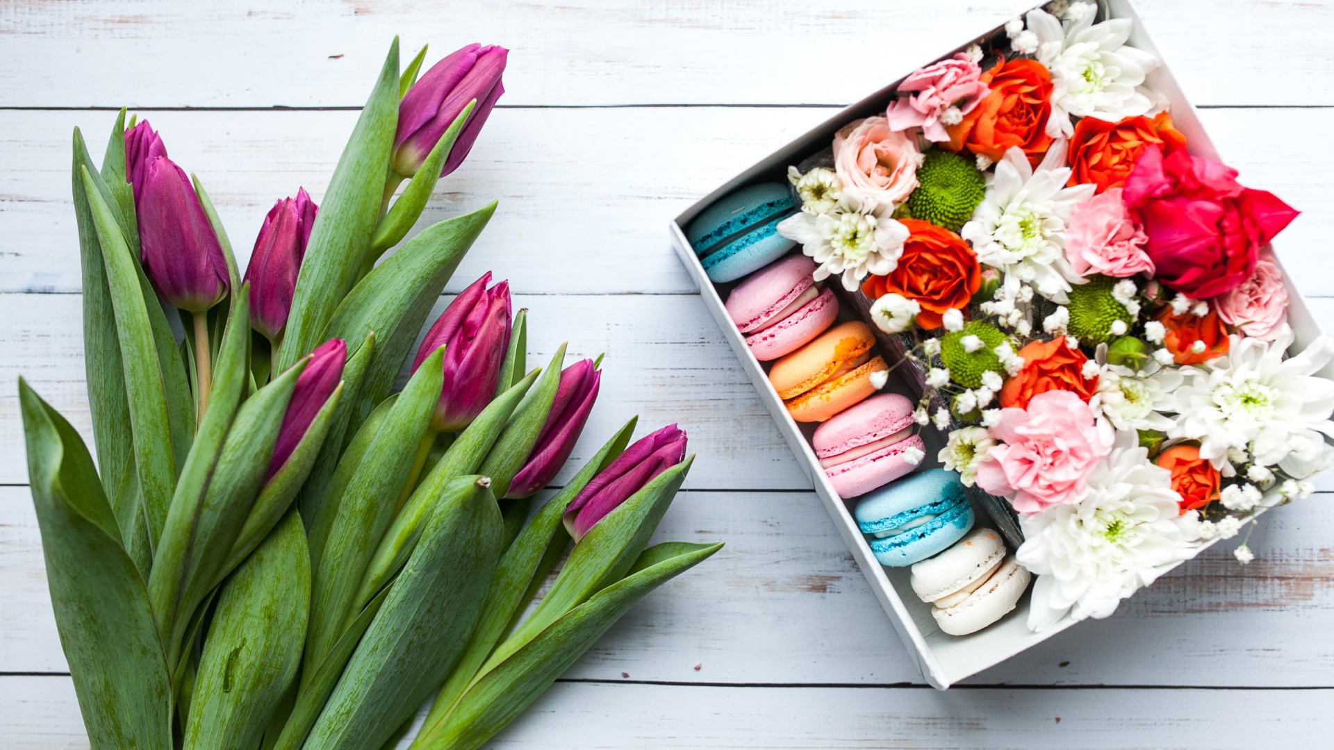 Букет сиреневых тюльпанов на столе с коробкой с макарунами
