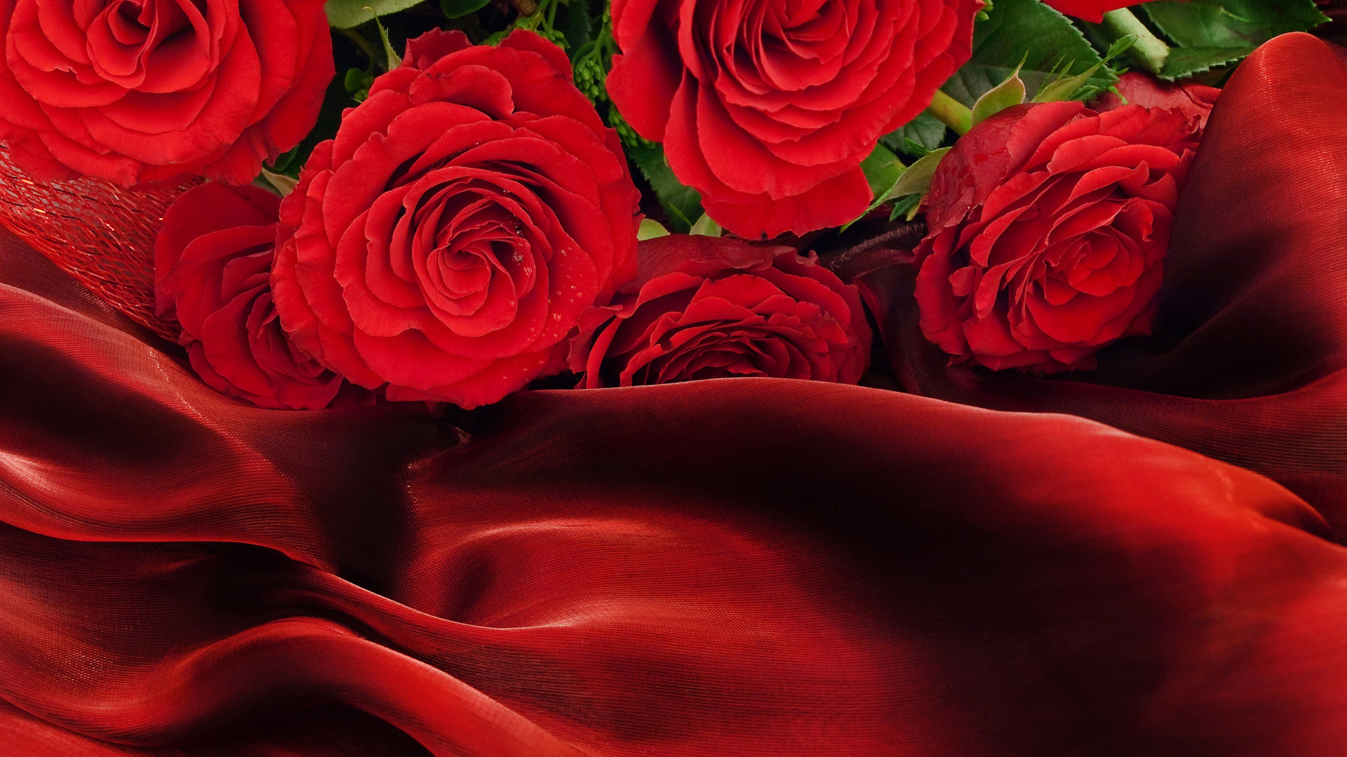 Букет красных роз на красном шелковом покрывале