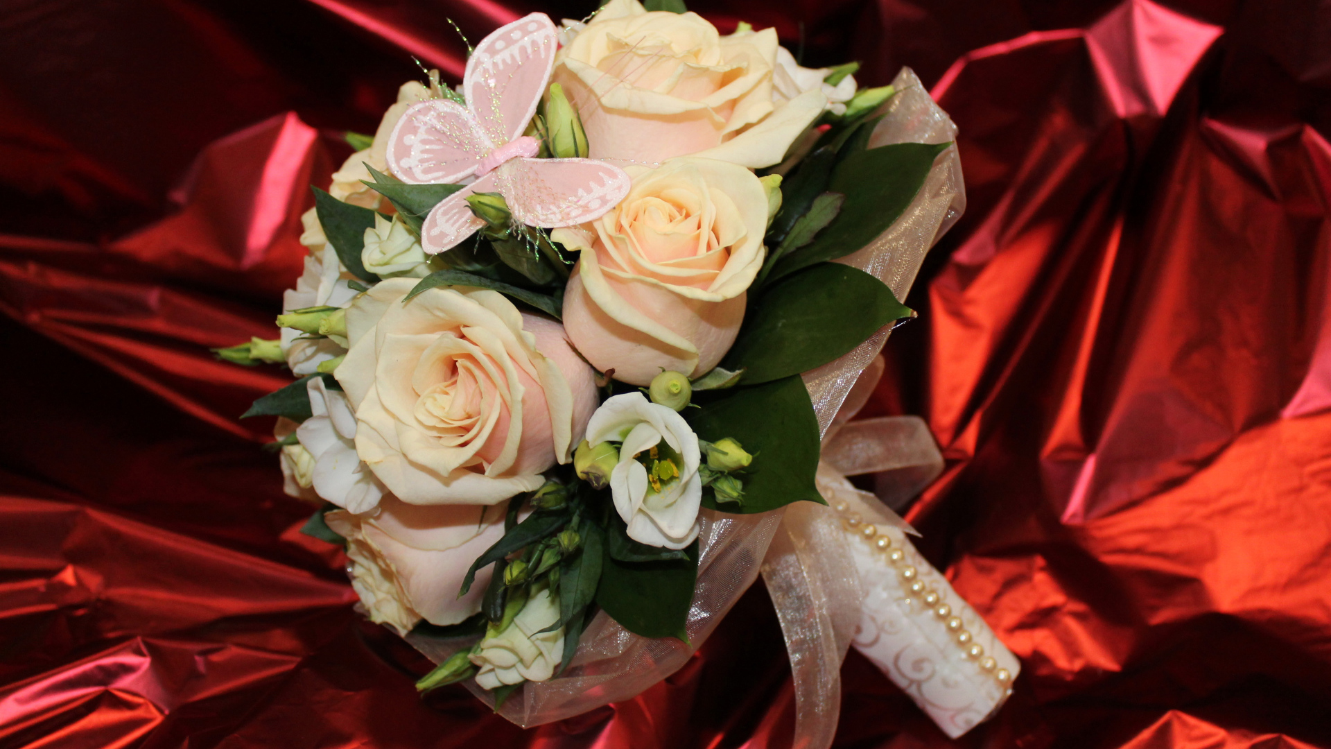 Нежный свадебный букет с цветами розовой розы и эустомы на красном фоне