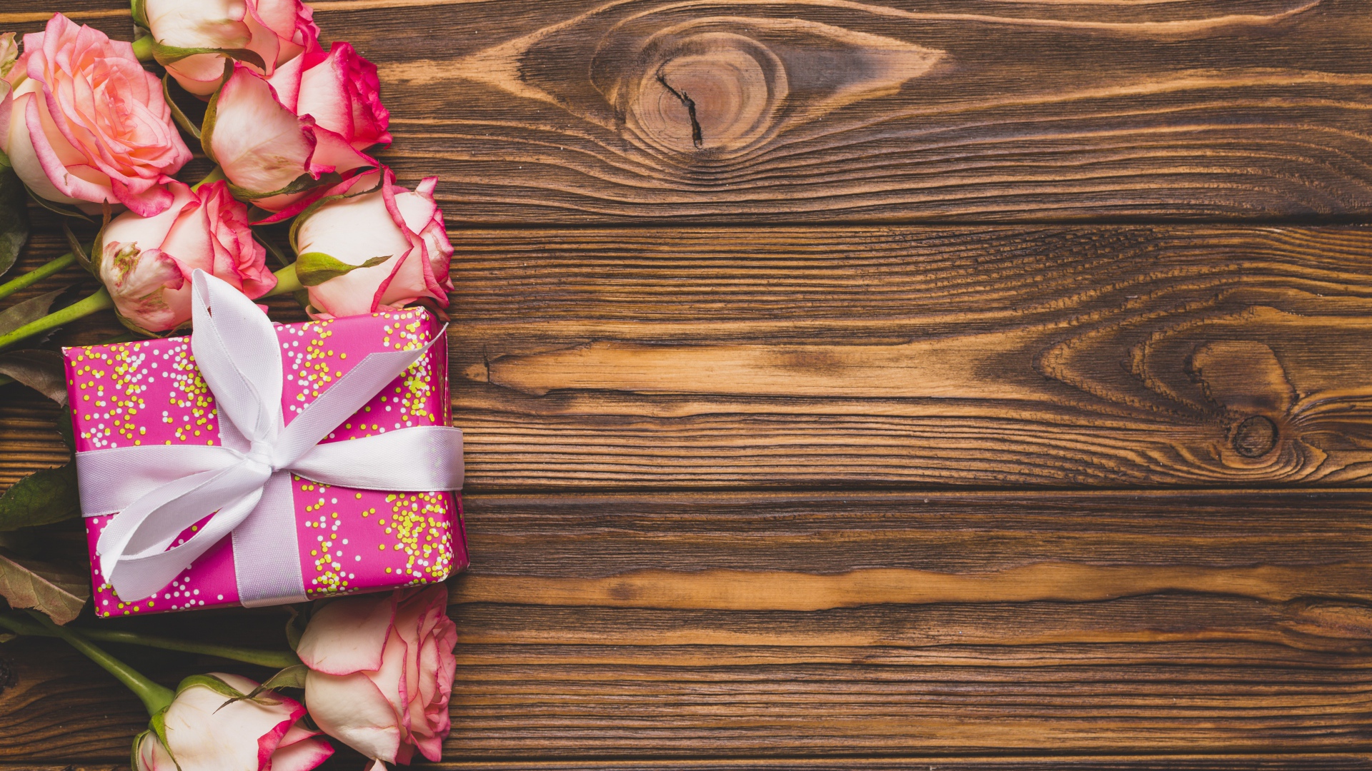 Подарочная коробка с букетом роз на деревянном фоне 
