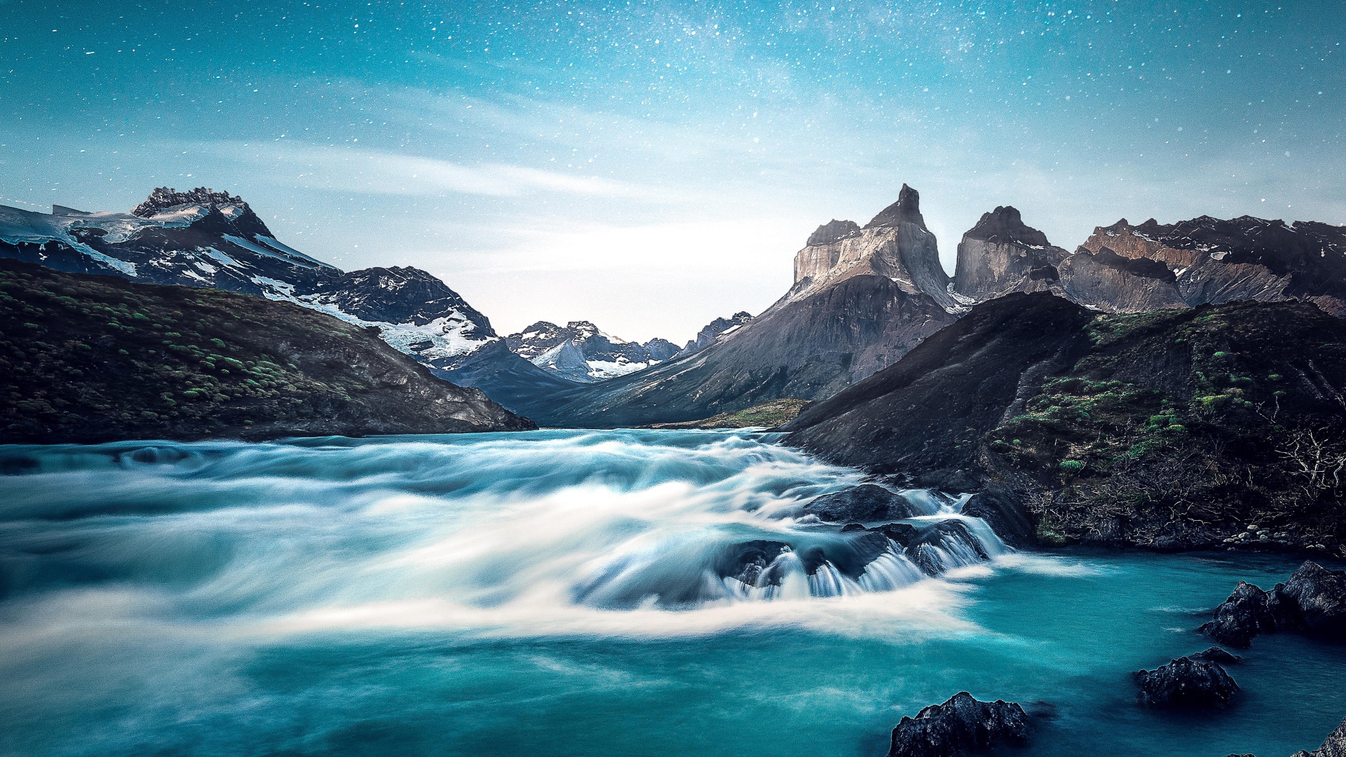 Быстрая вода к реке у гор на фоне голубого неба 