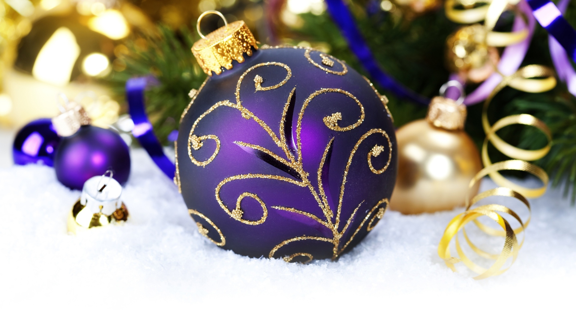 Красивая фиолетовая елочная игрушка лежит на снегу