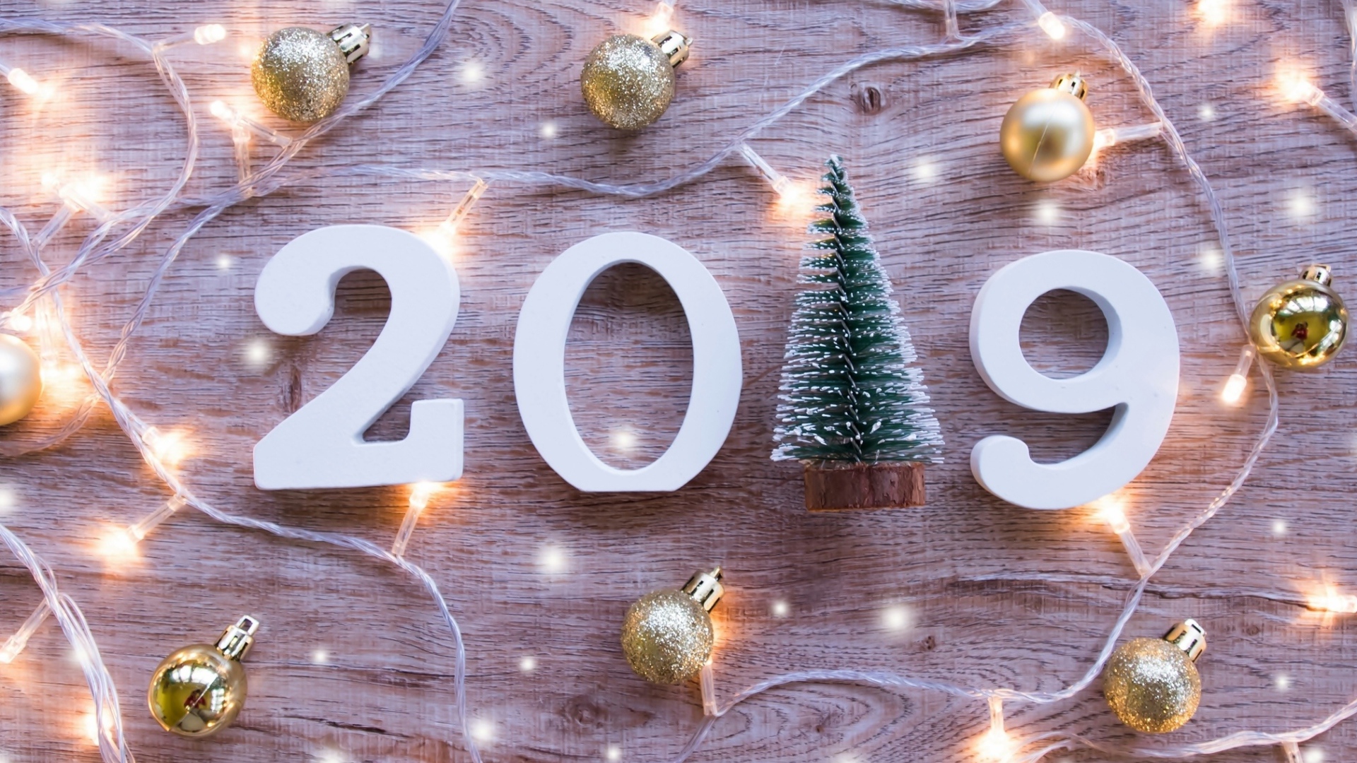 Цифры 2019 на деревянном фоне с елочными игрушками и гирляндой