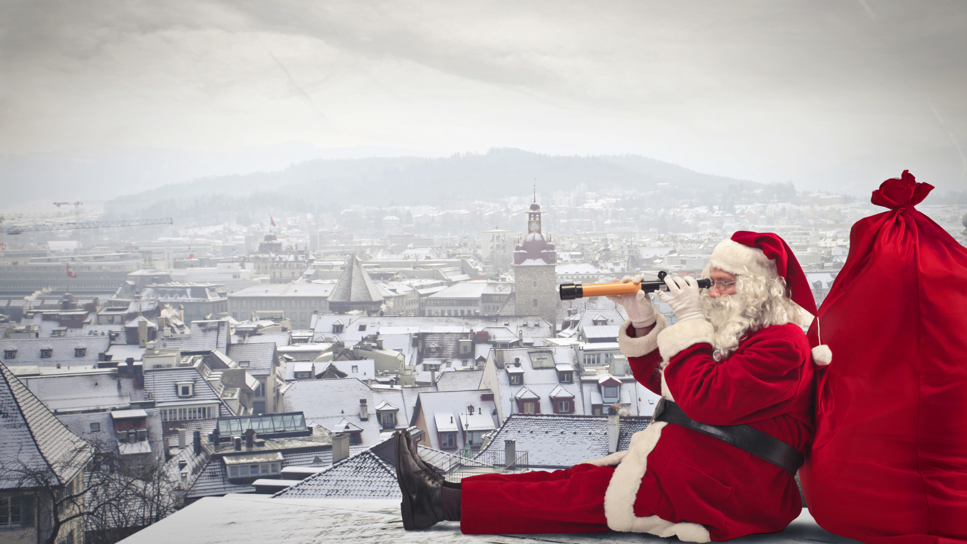 Санта Клаус сидит на крыше дома с большим красным мешком