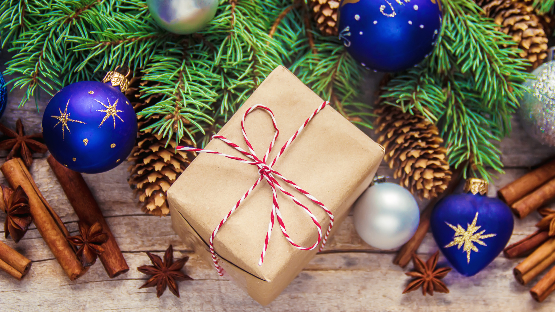 Еловая ветка с игрушками на столе с корицей и подарком на Новый год 