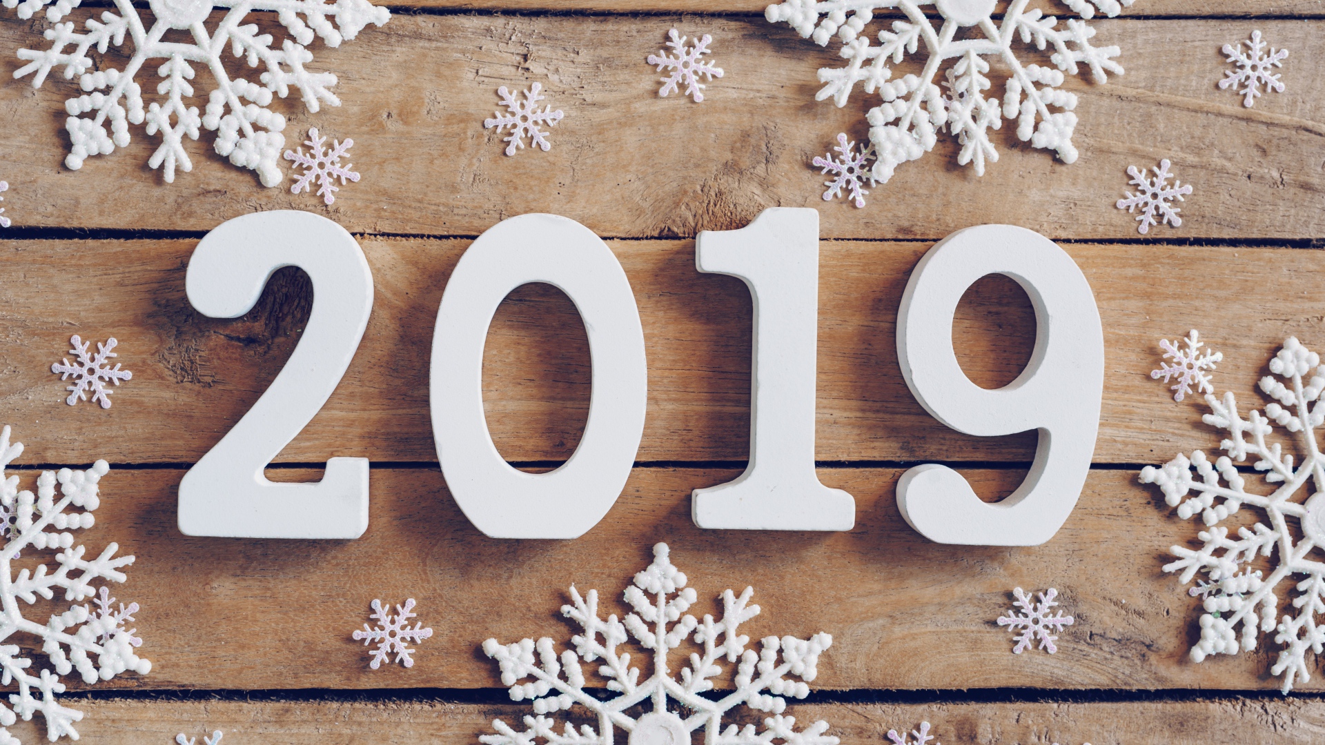 Белые цифры 2019 на деревянном столе с белыми снежинками