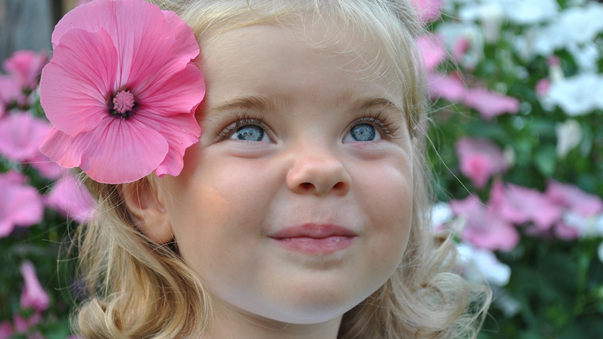 Милая маленькая девочка блондинка с цветком в волосах