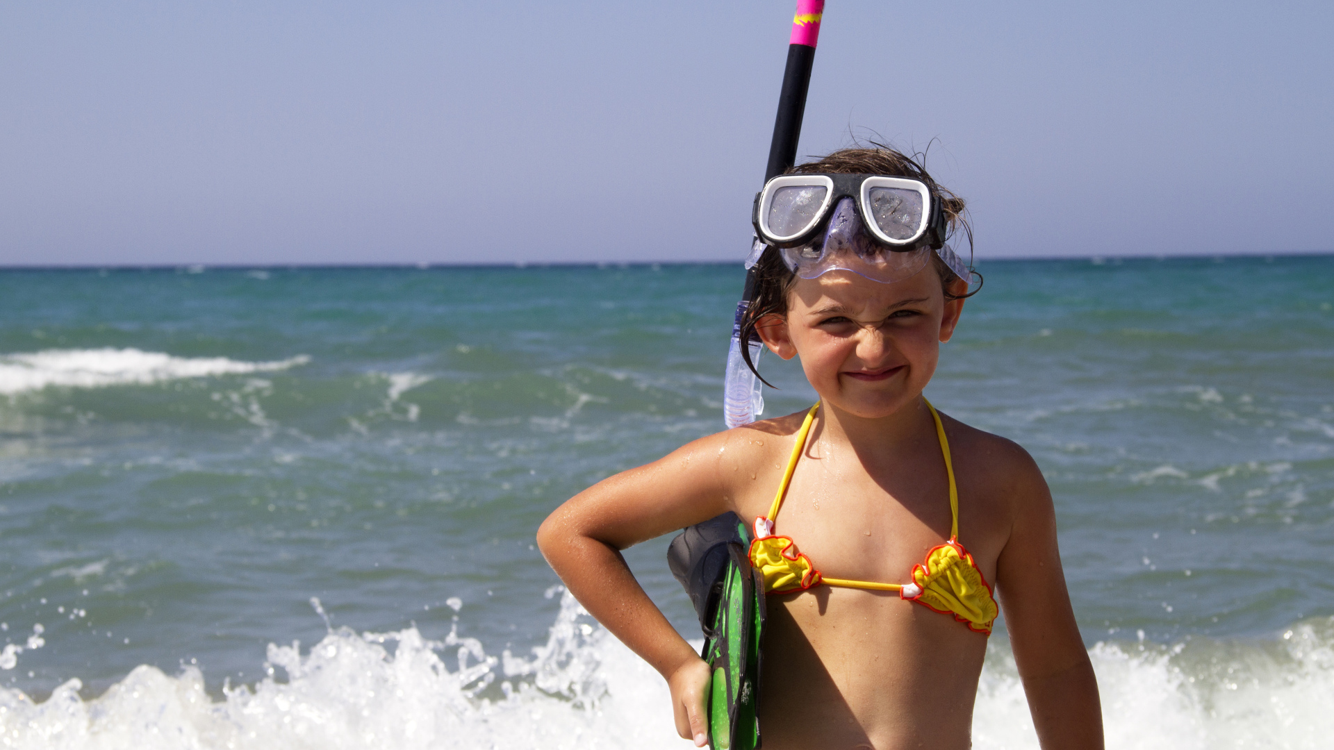 Маленькая девочка в очках и с ластами на море