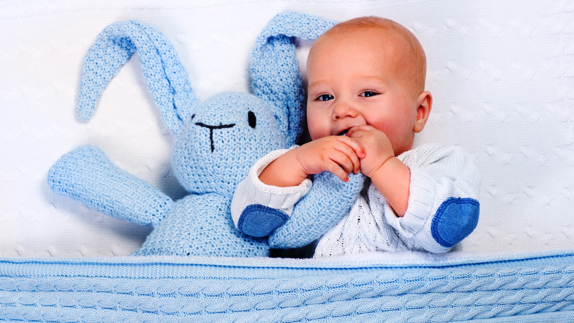 Маленький грудной ребенок грызет мягкую игрушку 