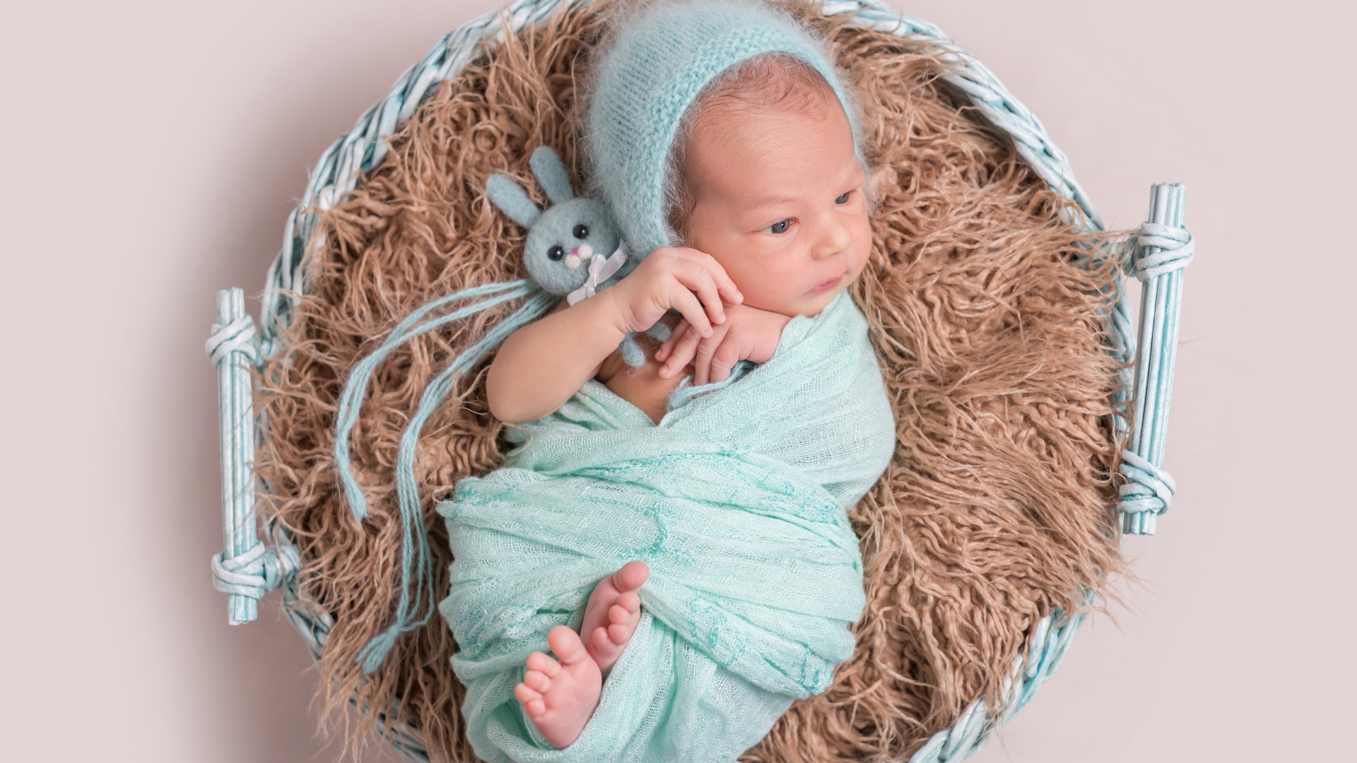 Маленький ребенок в корзине на сером фоне