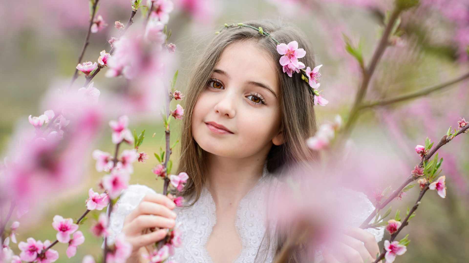 Красивая кареглазая девочка с розовыми цветами на дереве