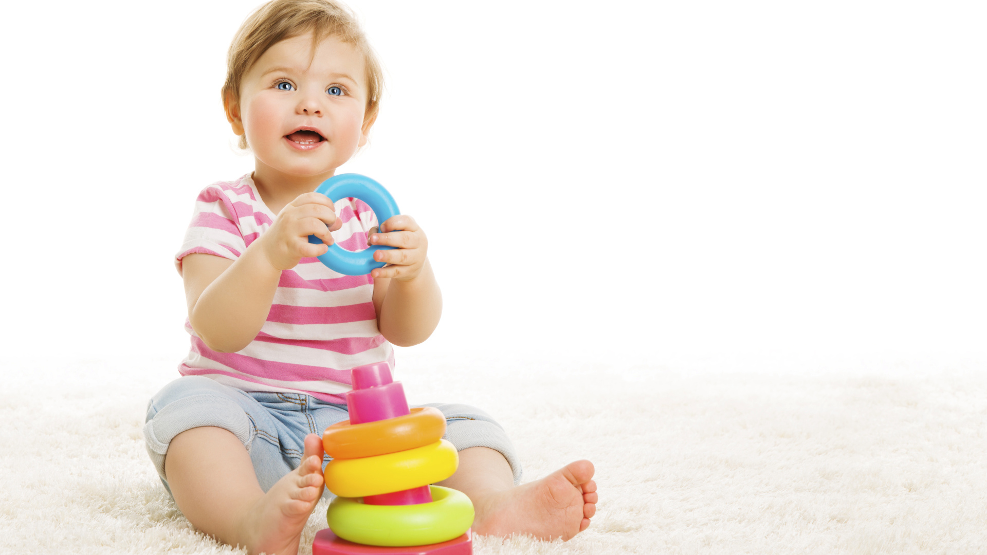 Голубоглазый маленький мальчик с игрушкой на белом фоне