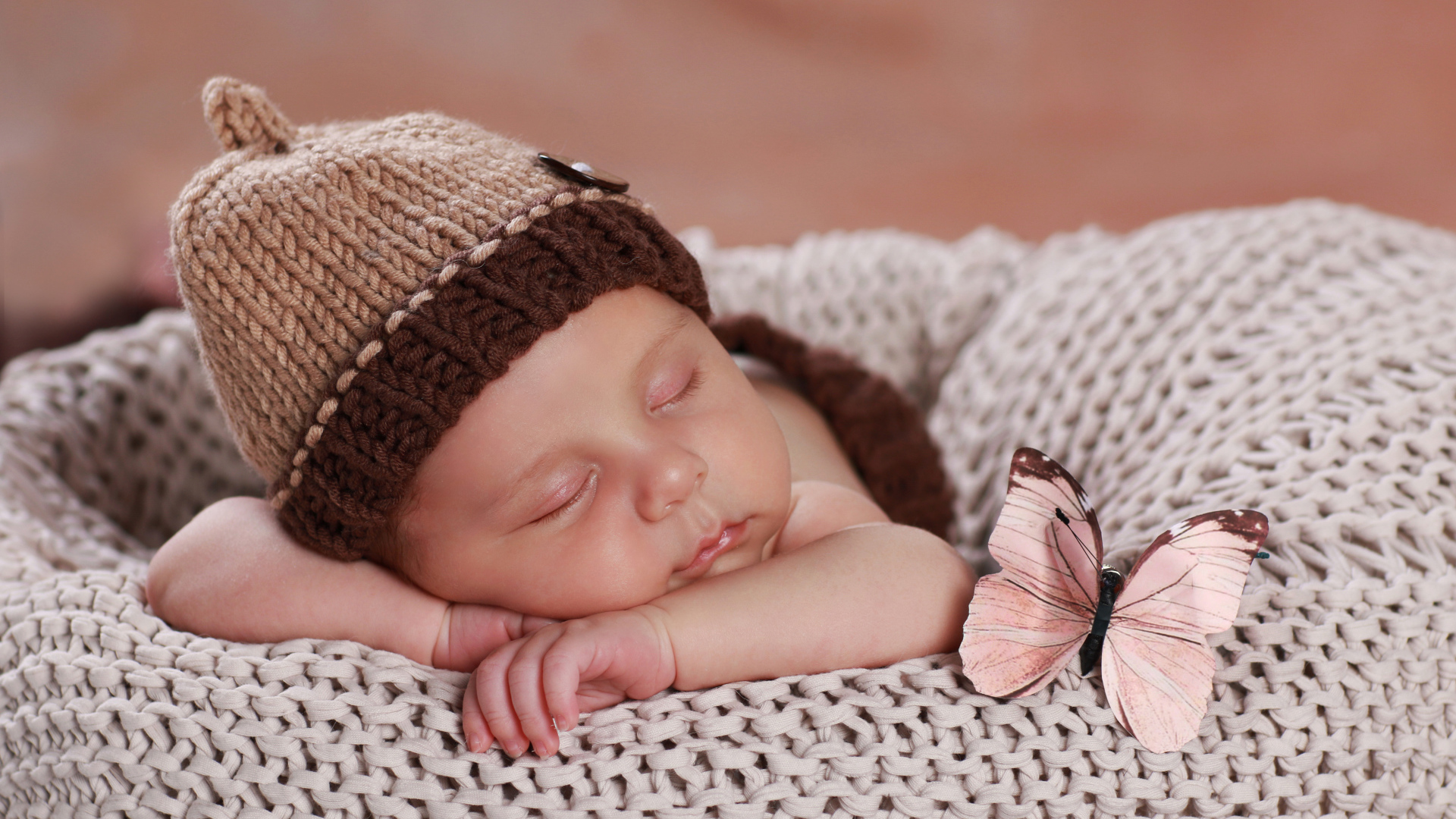 Милый спящий ребенок в коричневой вязаной шапке 