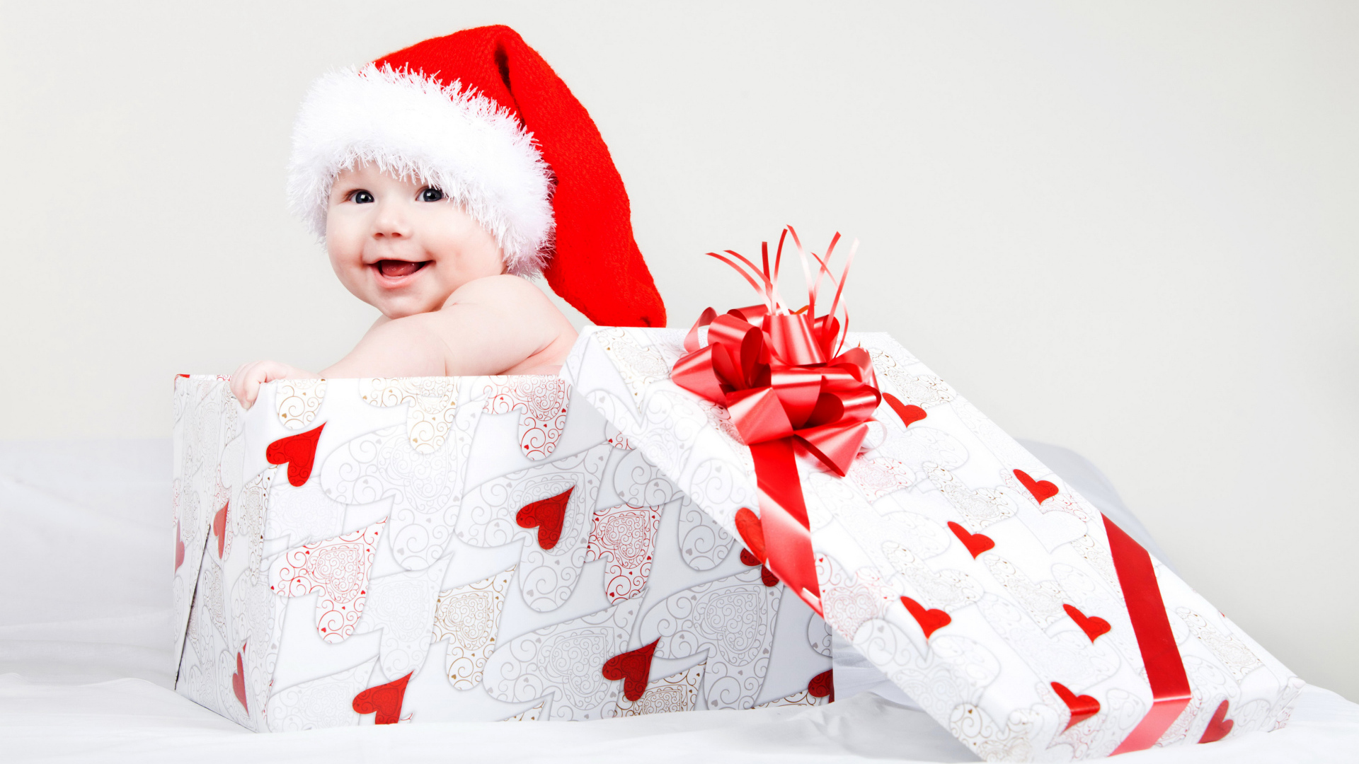 Маленький ребенок в новогоднем костюме в коробке для подарка на сером фоне
