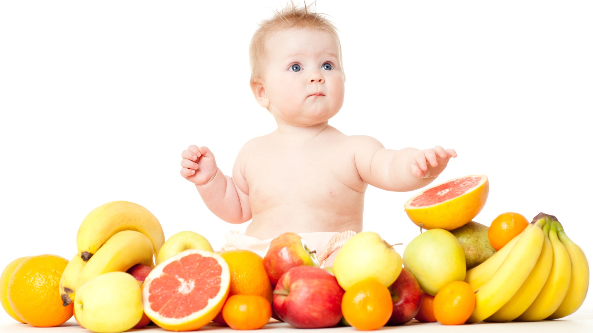 Маленький голубоглазый ребенок с фруктами на белом фоне