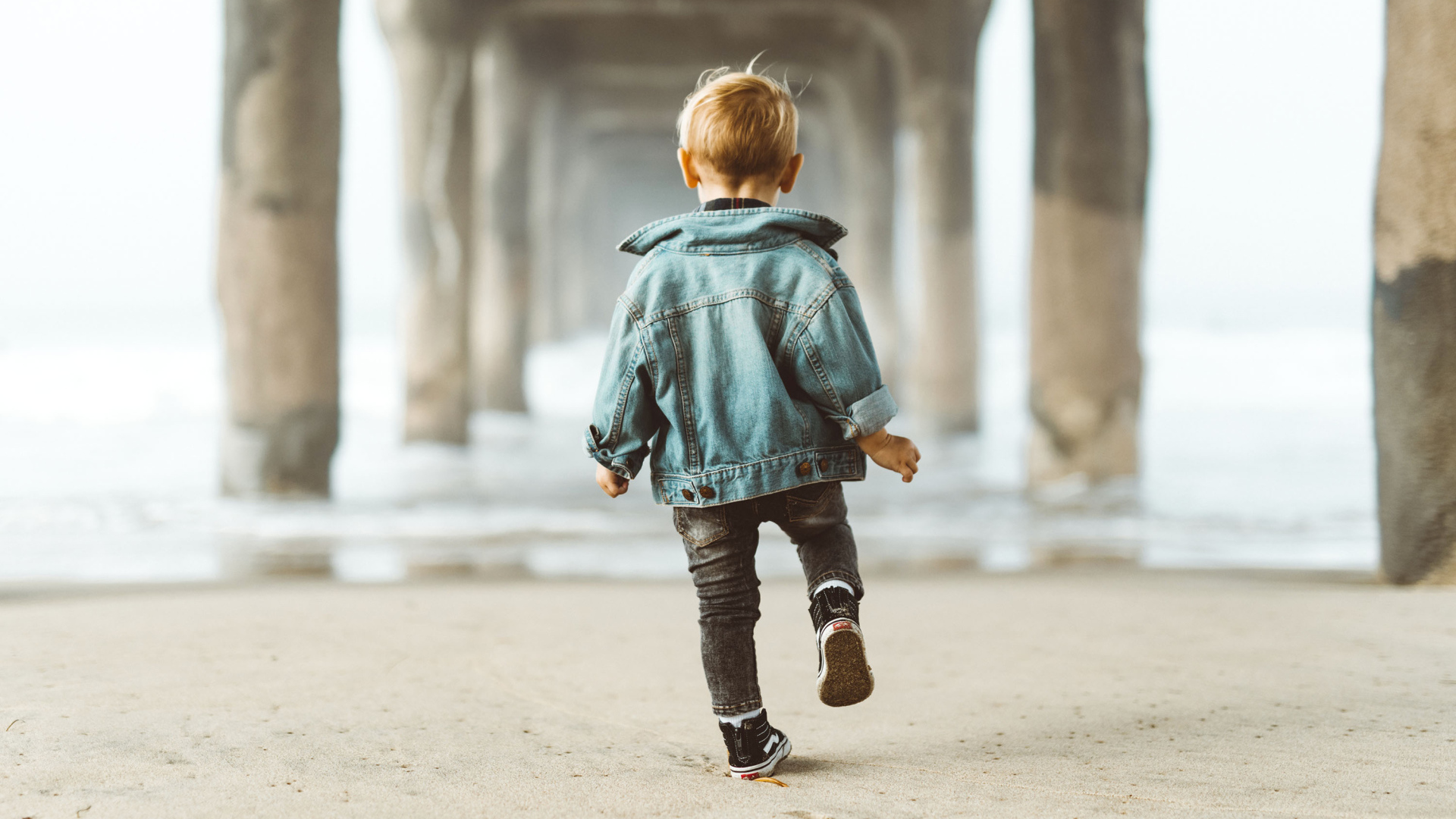 Маленький мальчик в джинсовой куртке спиной