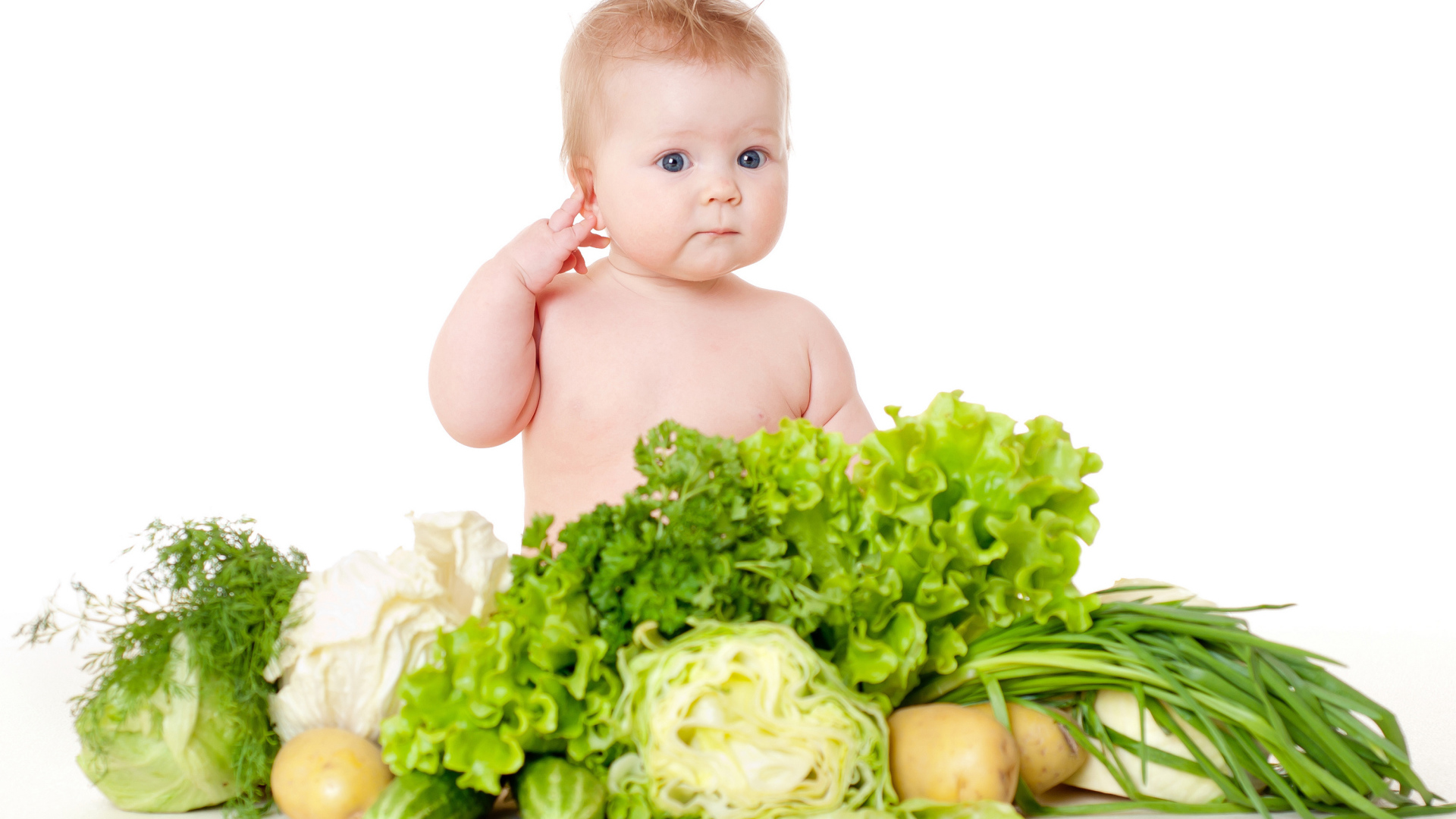 Маленький ребенок с овощами и зеленью на белом фоне