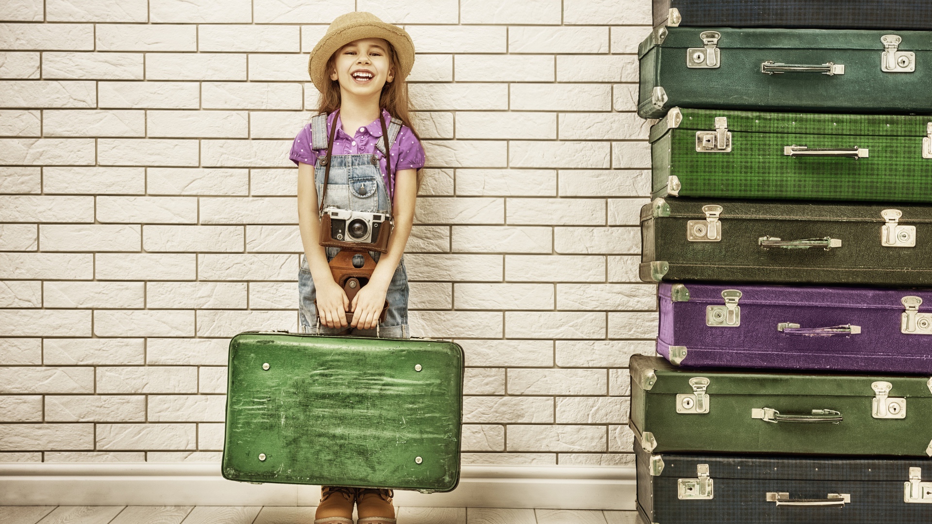 Маленькая девочка у стены с большими чемоданами