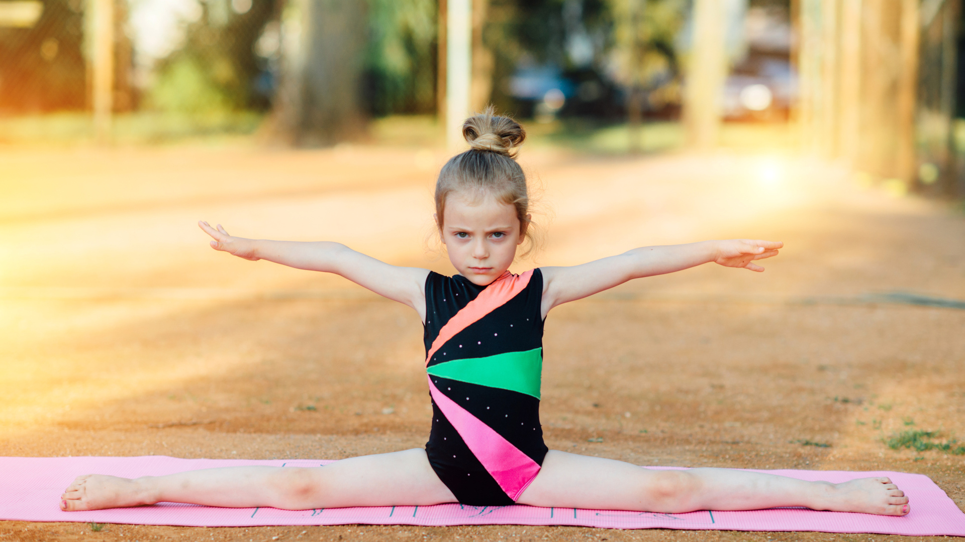 Маленькая девочка гимнастка сидит на шпагате 