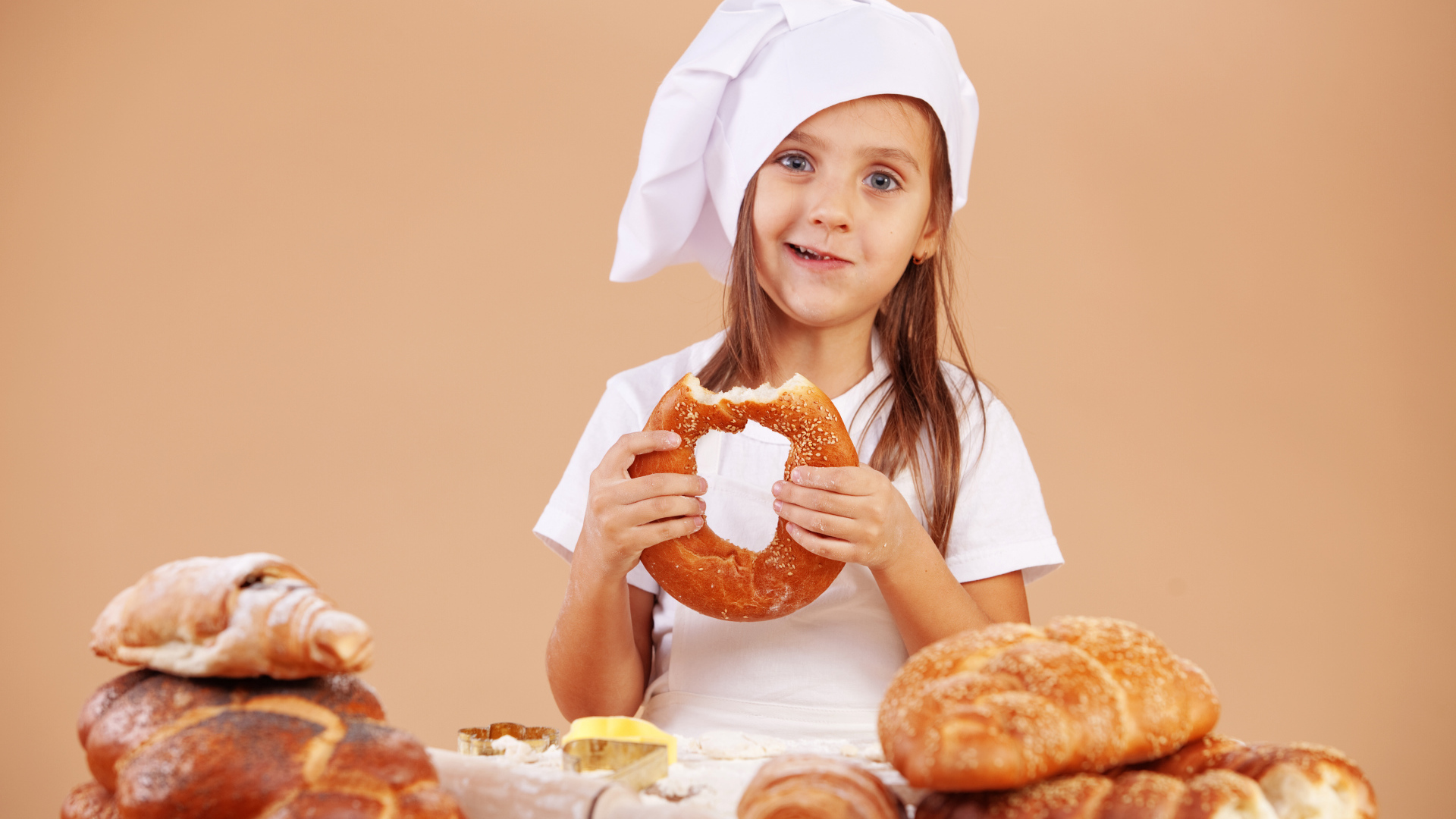 Маленькая девочка в костюме повара и свежей выпечкой