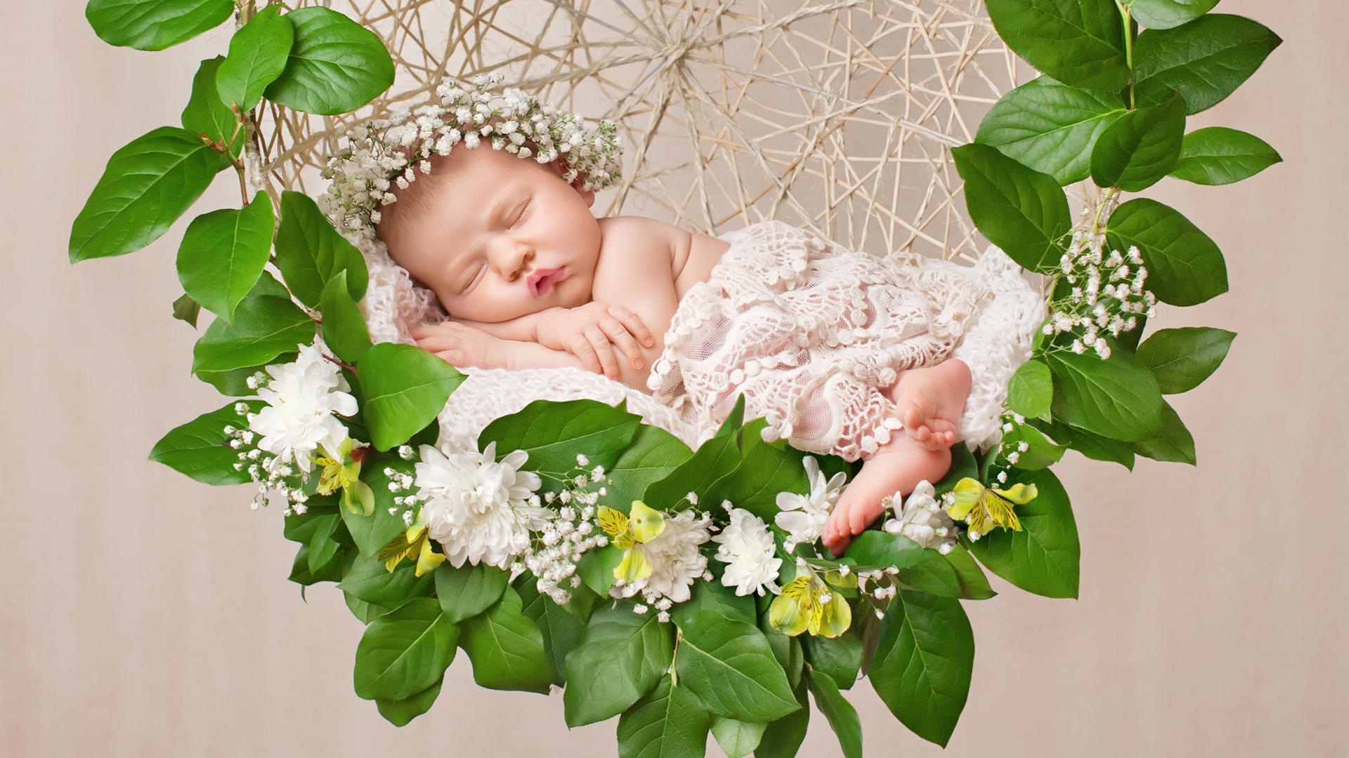 Маленькая девочка спит в колыбеле украшенной зелеными листьями