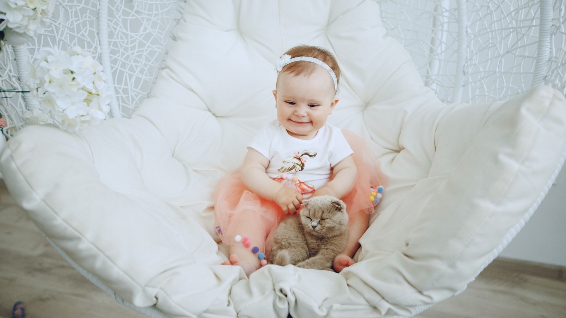 Маленький улыбающийся ребенок с котом сидит в белом кресле