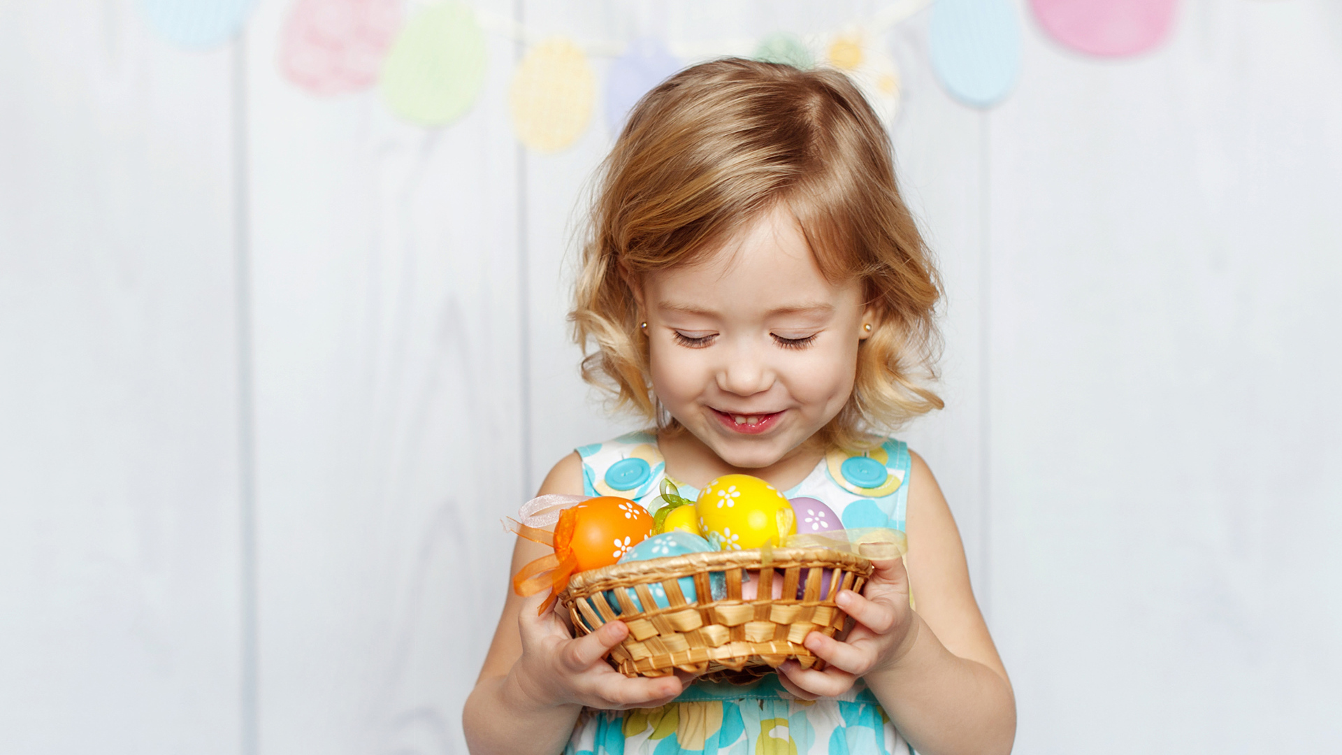 Маленькая улыбающаяся девочка с пасхальными яйцами в руках