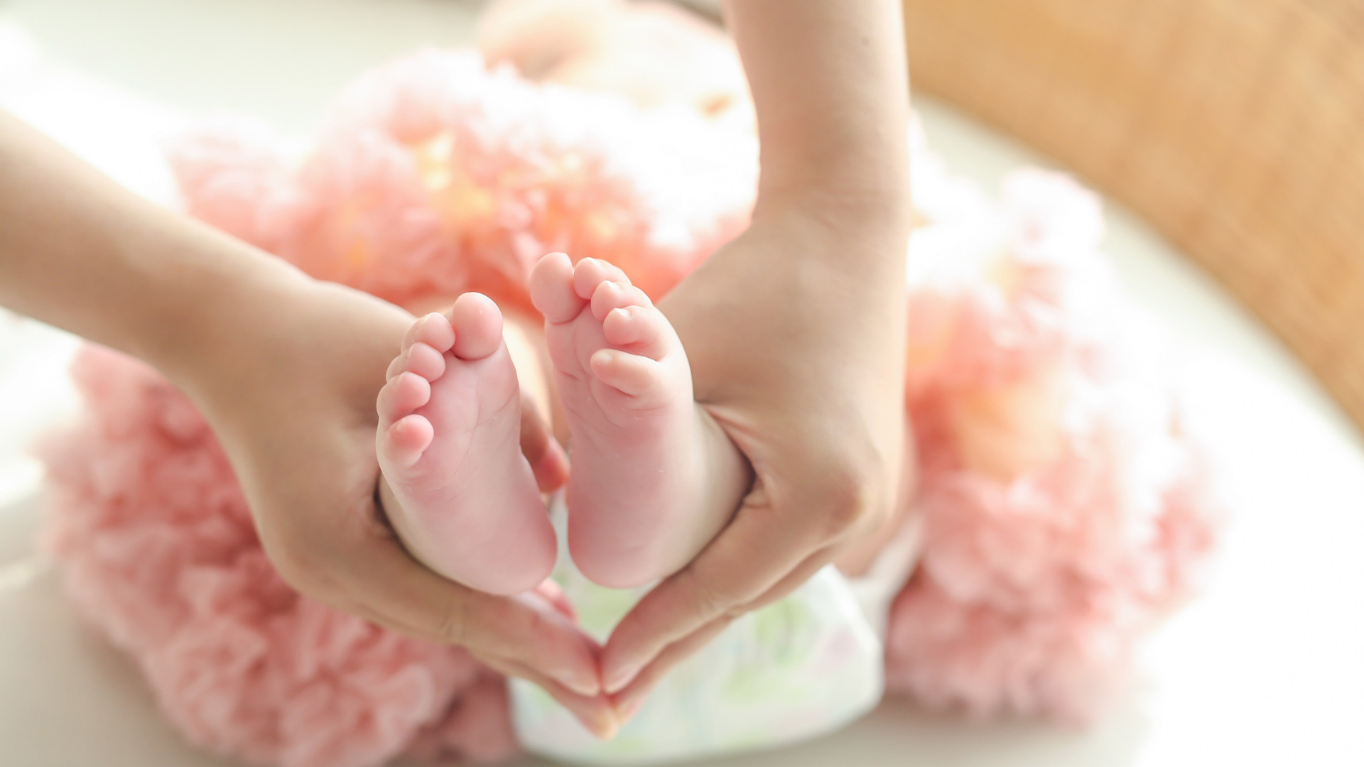 Маленькие ножки новорожденного в ладонях у мамы 