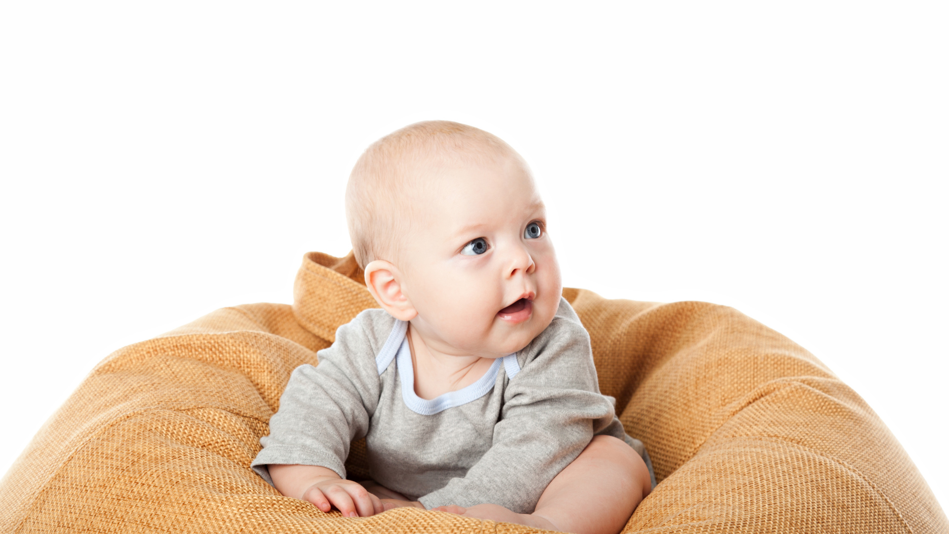 Младенец сидит на подушке на белом фоне