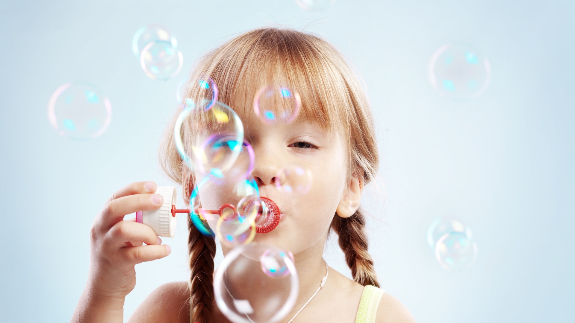 Девочка с косичками пускает мыльные пузыри