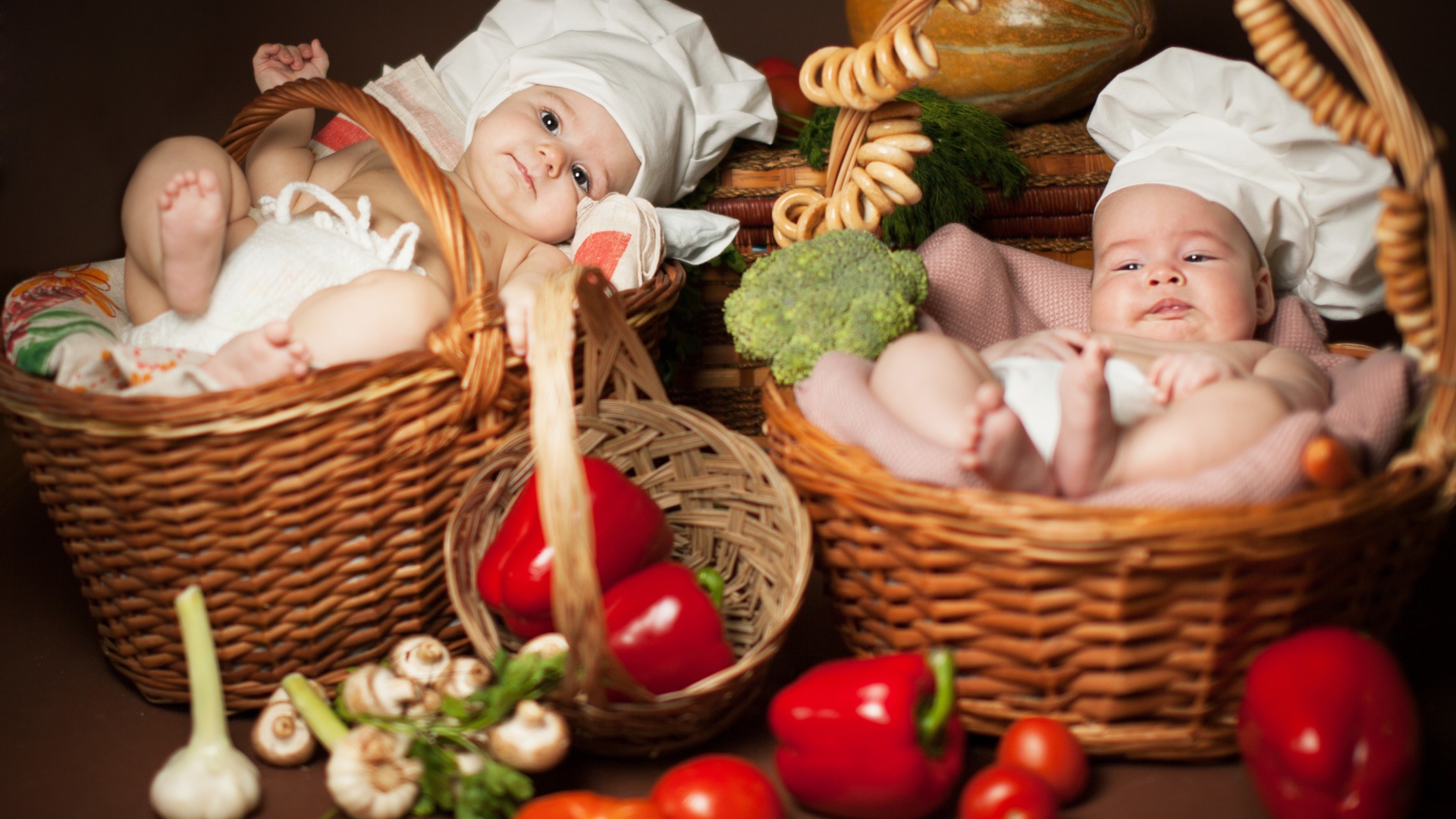 Два младенца в шапках повара лежат в корзинах с продуктами