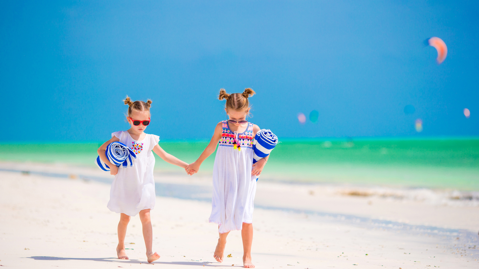 Две маленькие девочки идут по песку