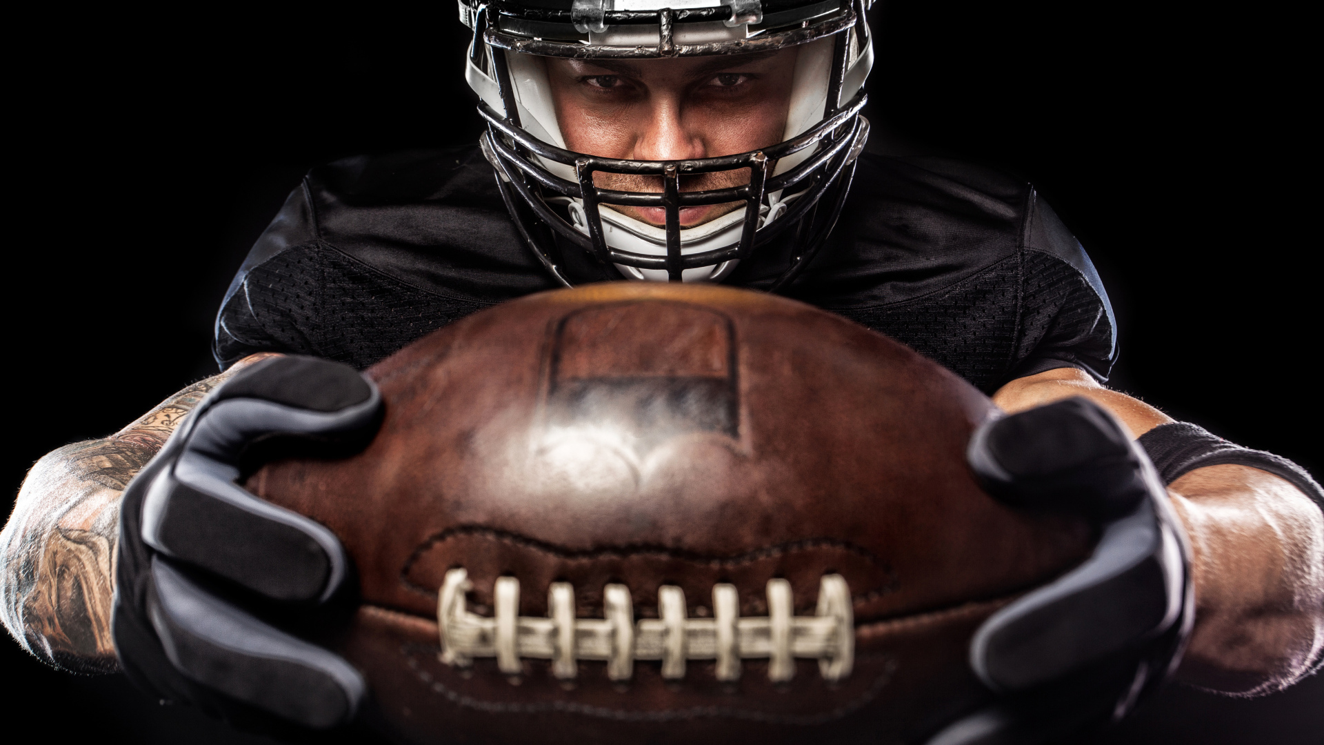 American football player with ball on black background