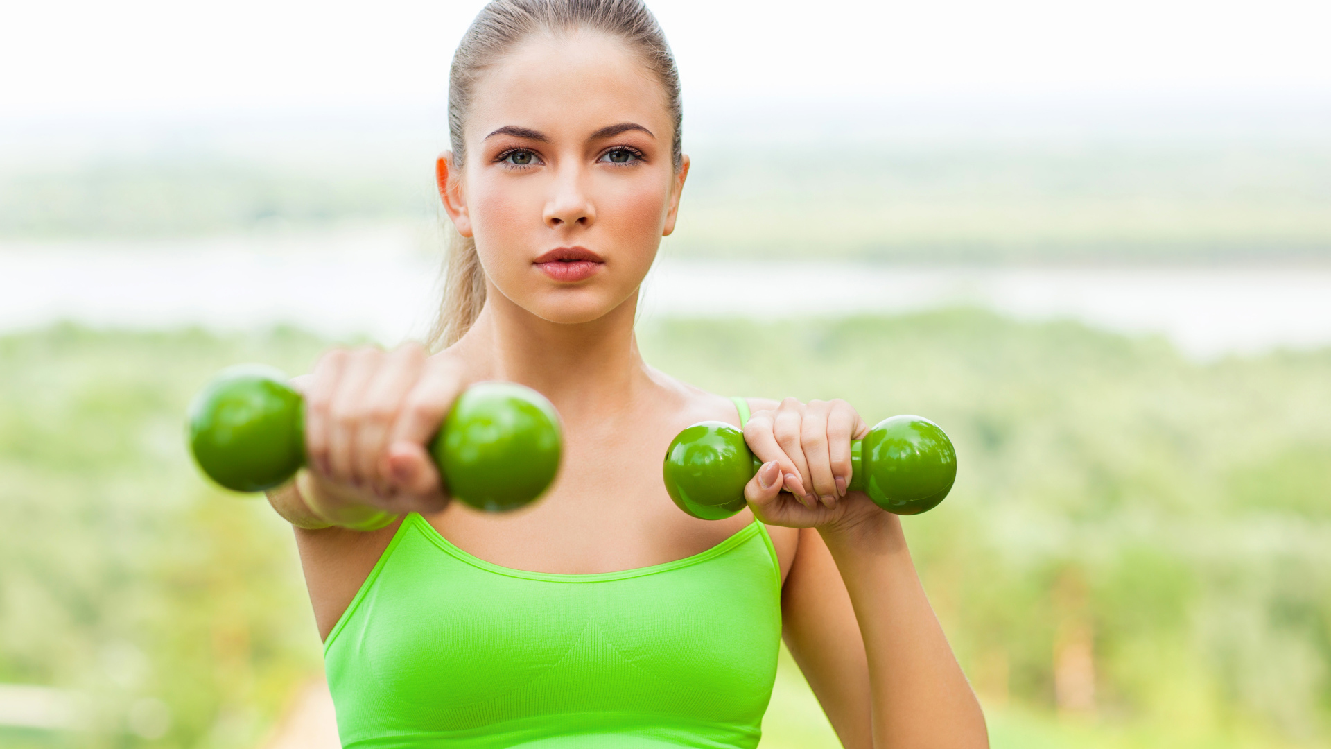 Молодая спортивная блондинка с гантелями в руках