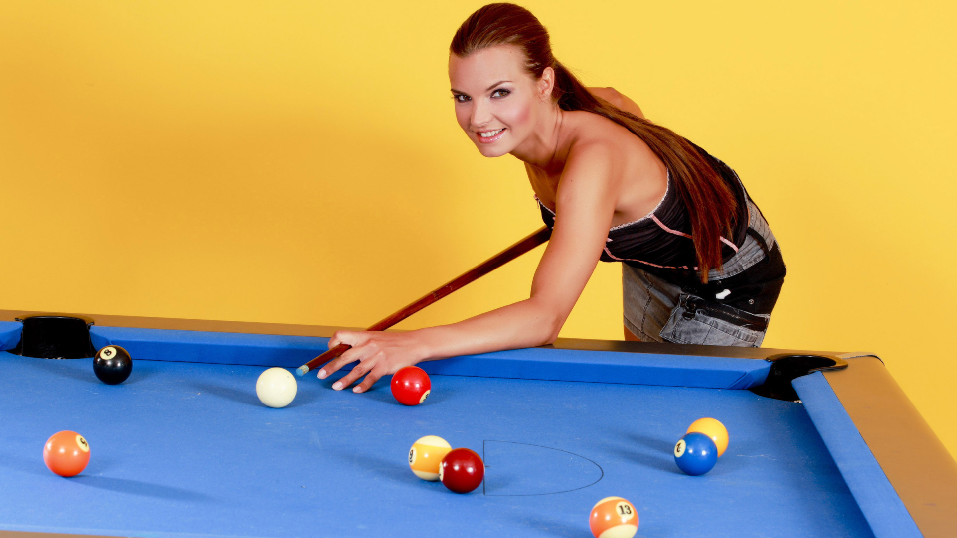 Молодая девушка играет в бильярд