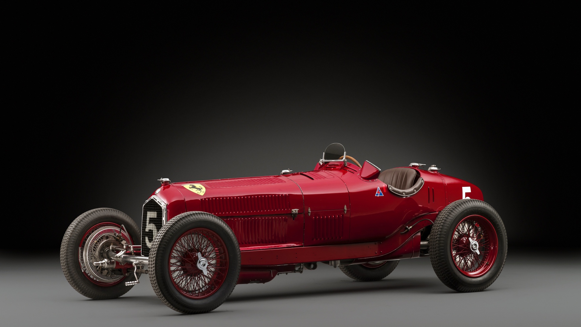 Красный ретро автомобиль Alfa Romeo на сером фоне