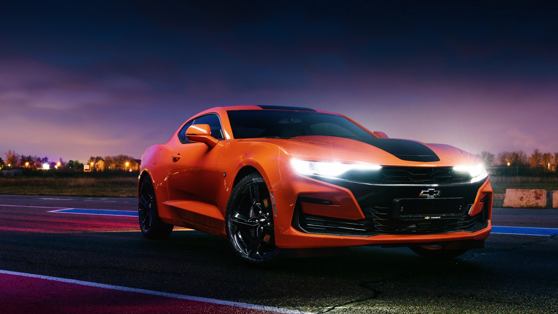 Оранжевый автомобиль Chevrolet Camaro, 2019 года с включенными фарами