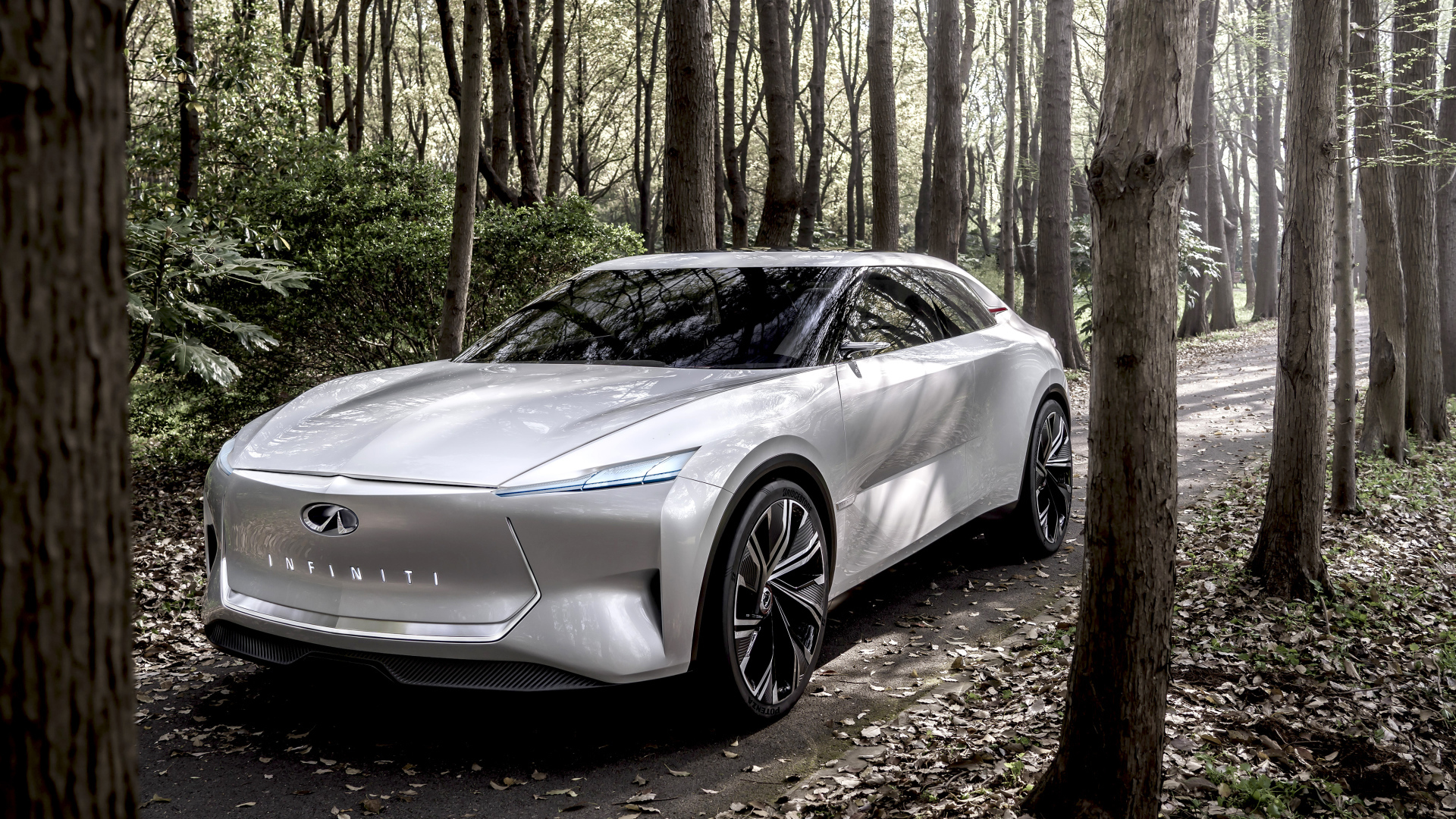 Серебристый автомобиль Infiniti Qs Inspiration 2019 года в лесу