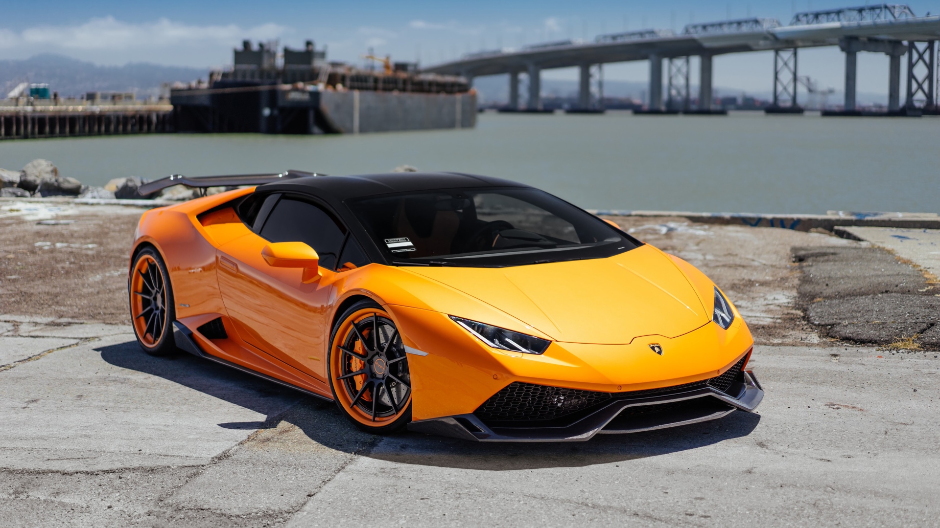 Оранжевый быстрый Lamborghini Huracan в порту у воды