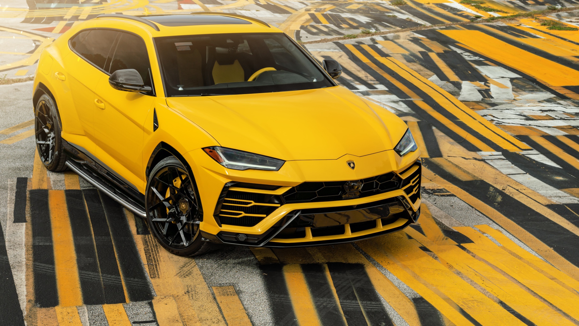 Желтый внедорожник Lamborghini Urus на разноцветном асфальте 