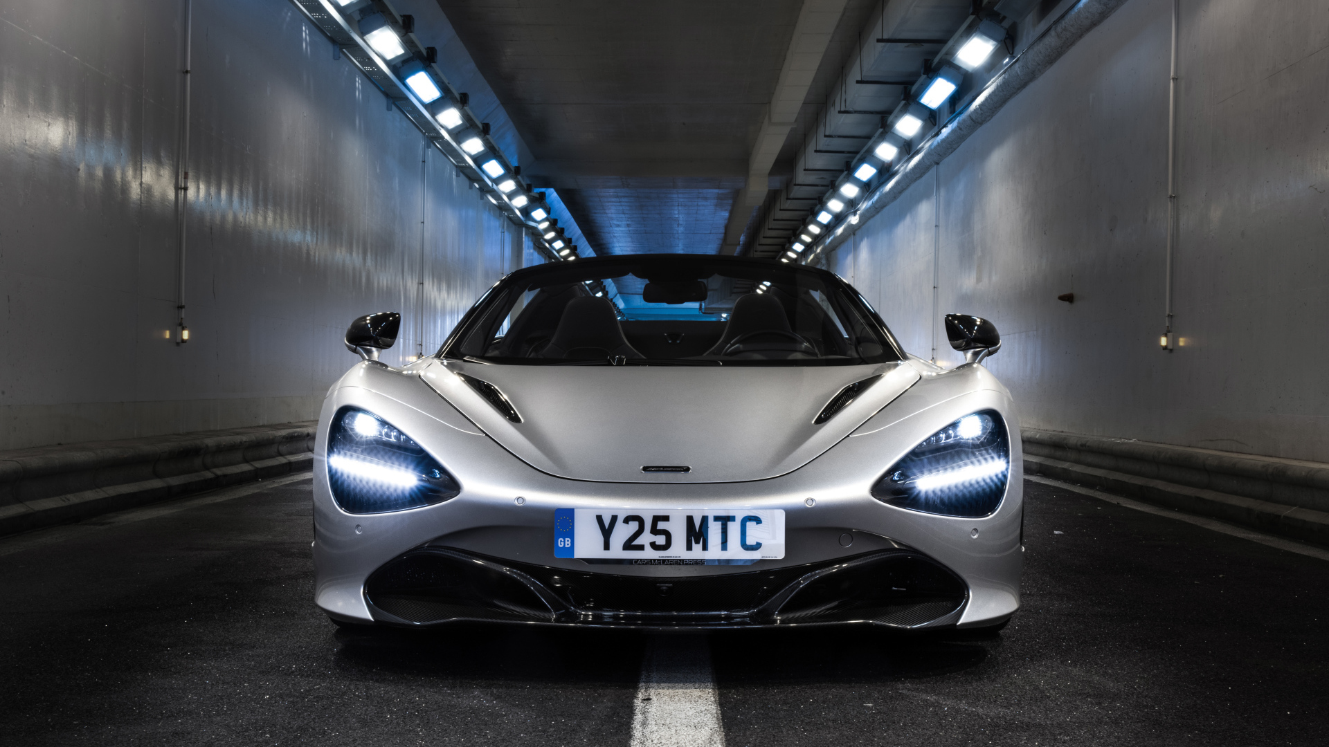 Серебристый спортивный автомобиль  McLaren 720S Spider, 2019 года в тоннеле