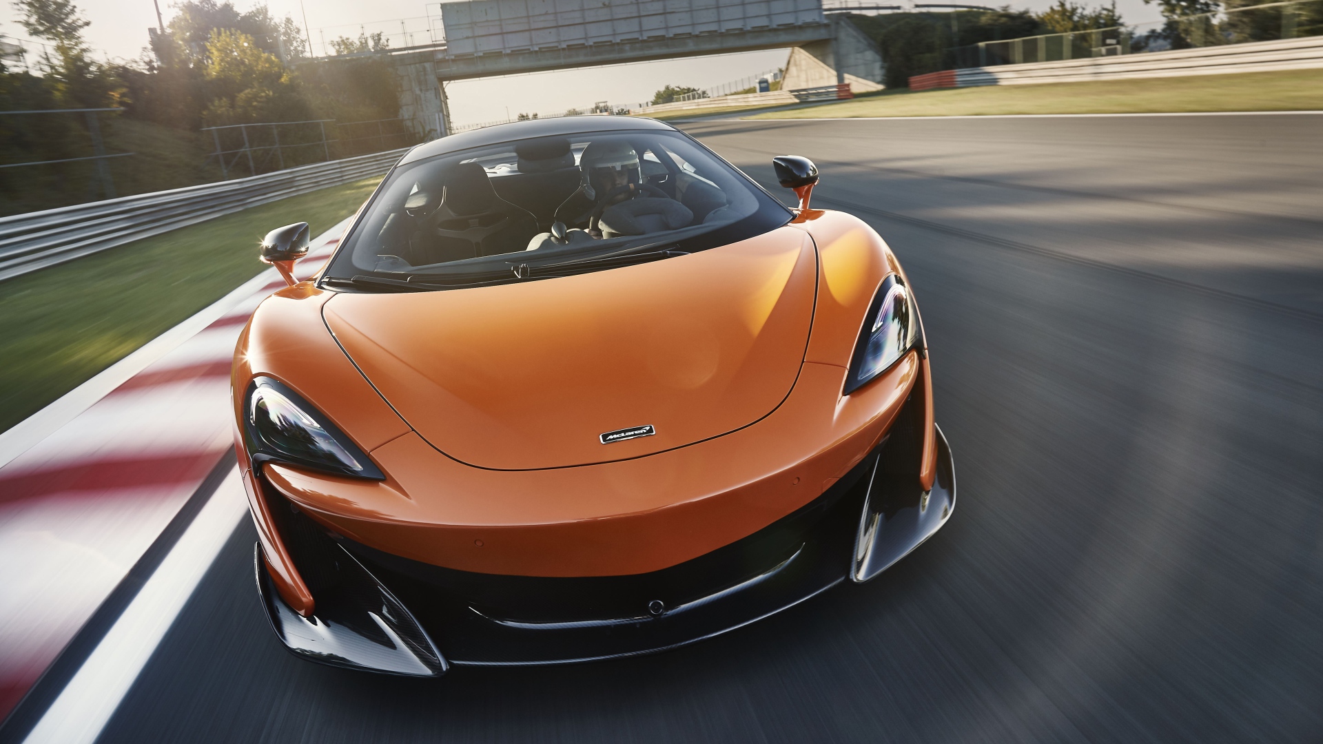 Спортивный оранжевый автомобиль McLaren 600LT 2019 года на трассе