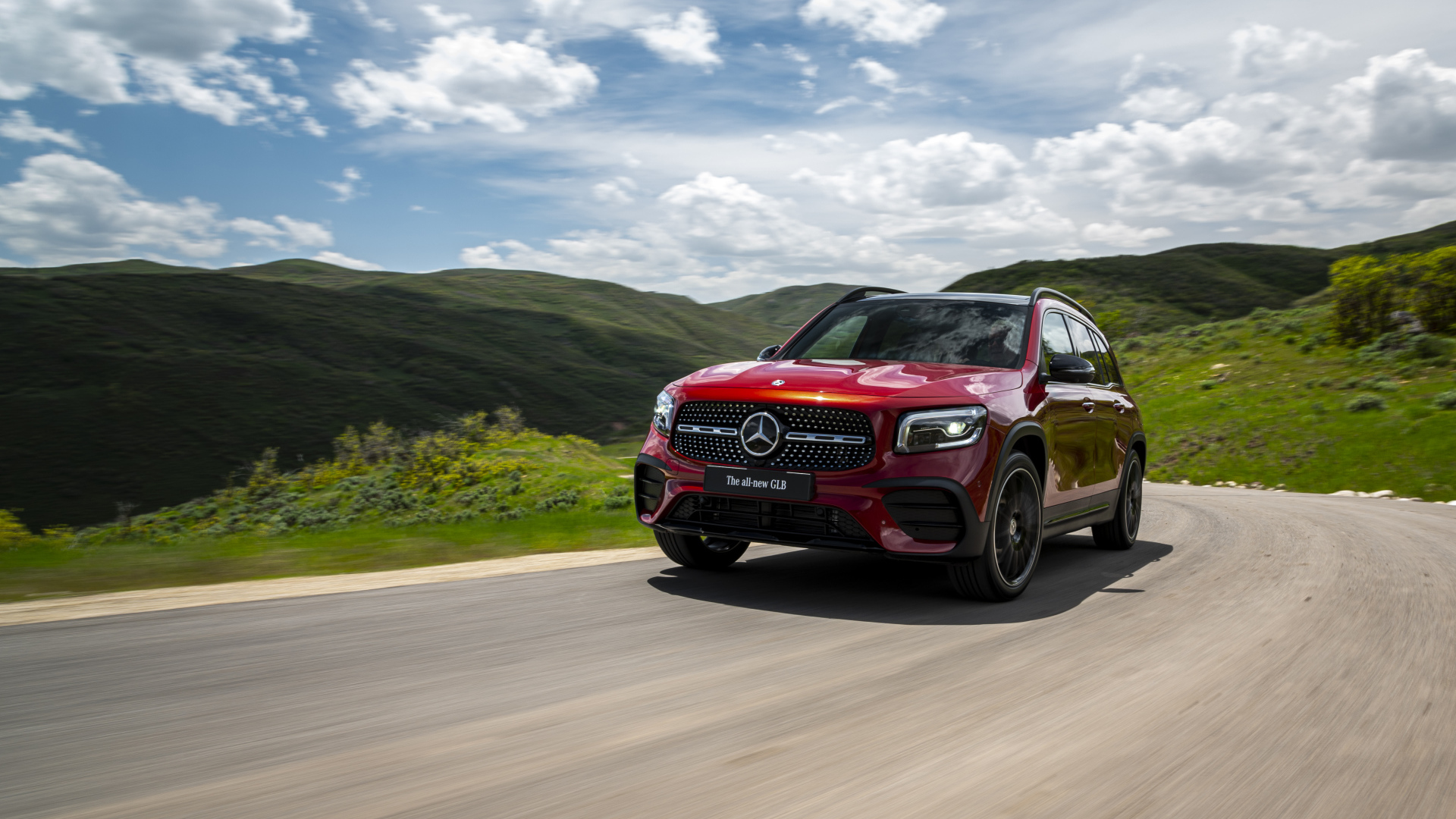 Красный автомобиль Mercedes-Benz GLB-Class  на фоне зеленых холмов